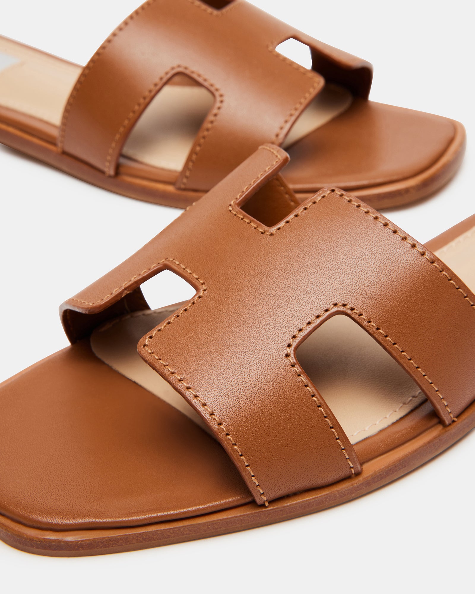 Top view of cognac leather slide sandals showcasing the geometric strap design.