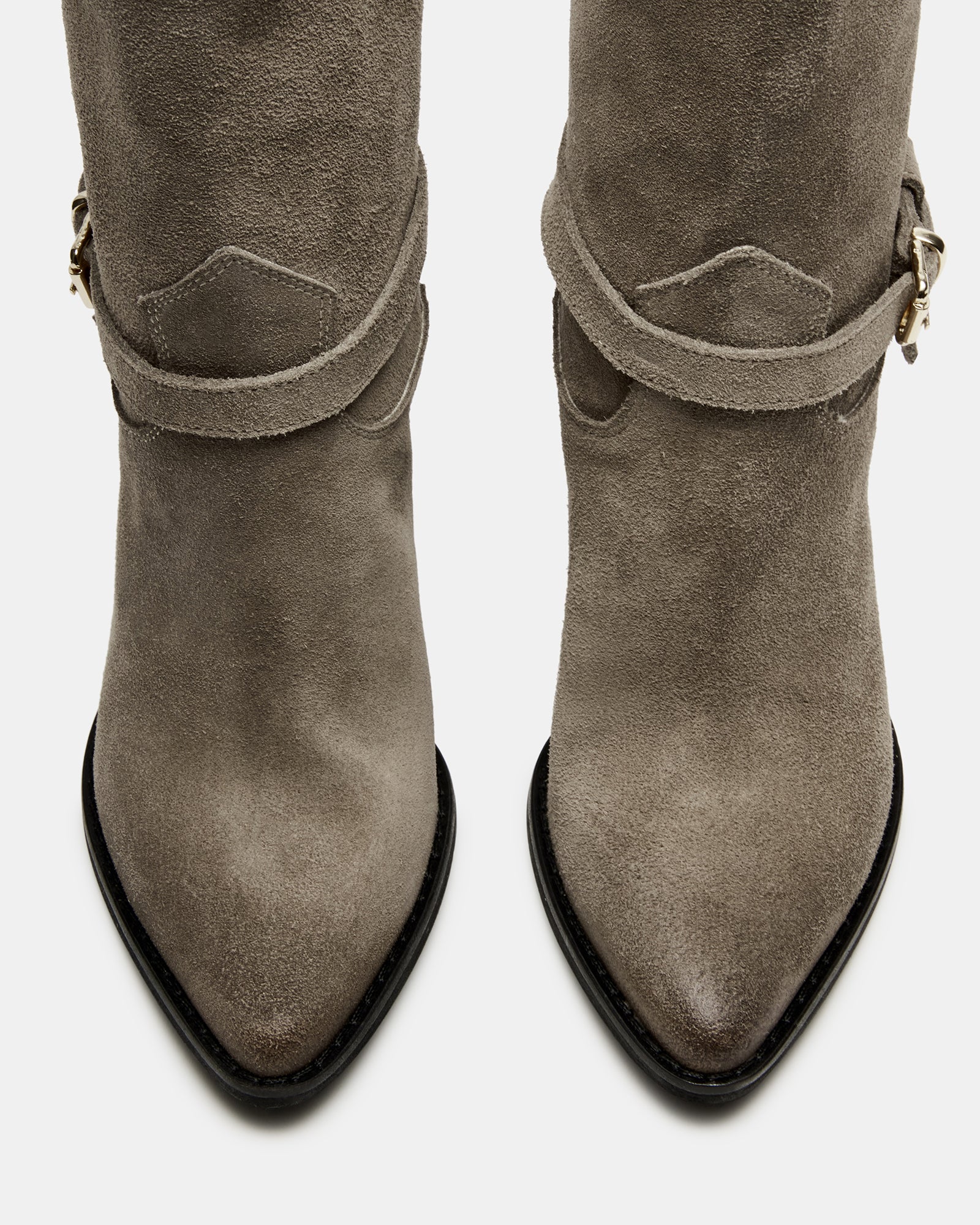 Side view of brown suede booties on a wooden floor, showcasing the stacked heel.