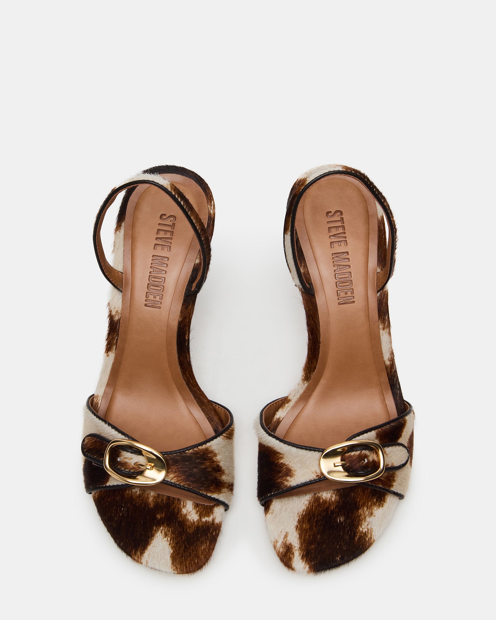 Side view of brown leather heeled sandals with cow print pattern and square toe design