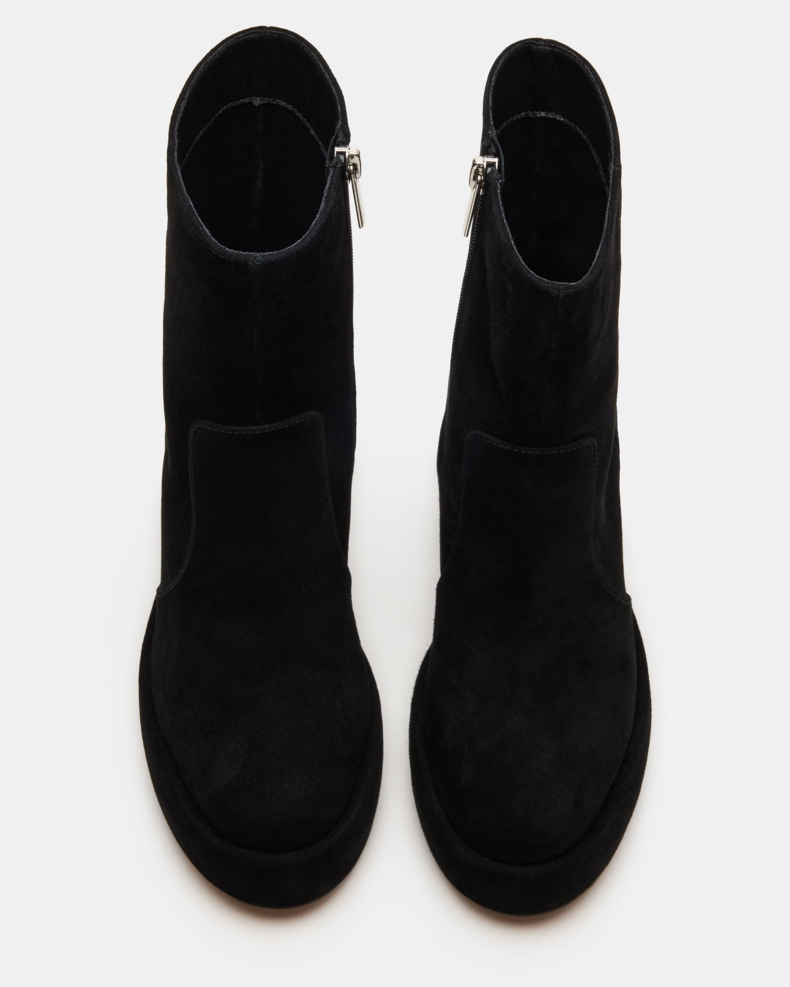 Side view of black suede platform ankle boots on a model wearing jeans.