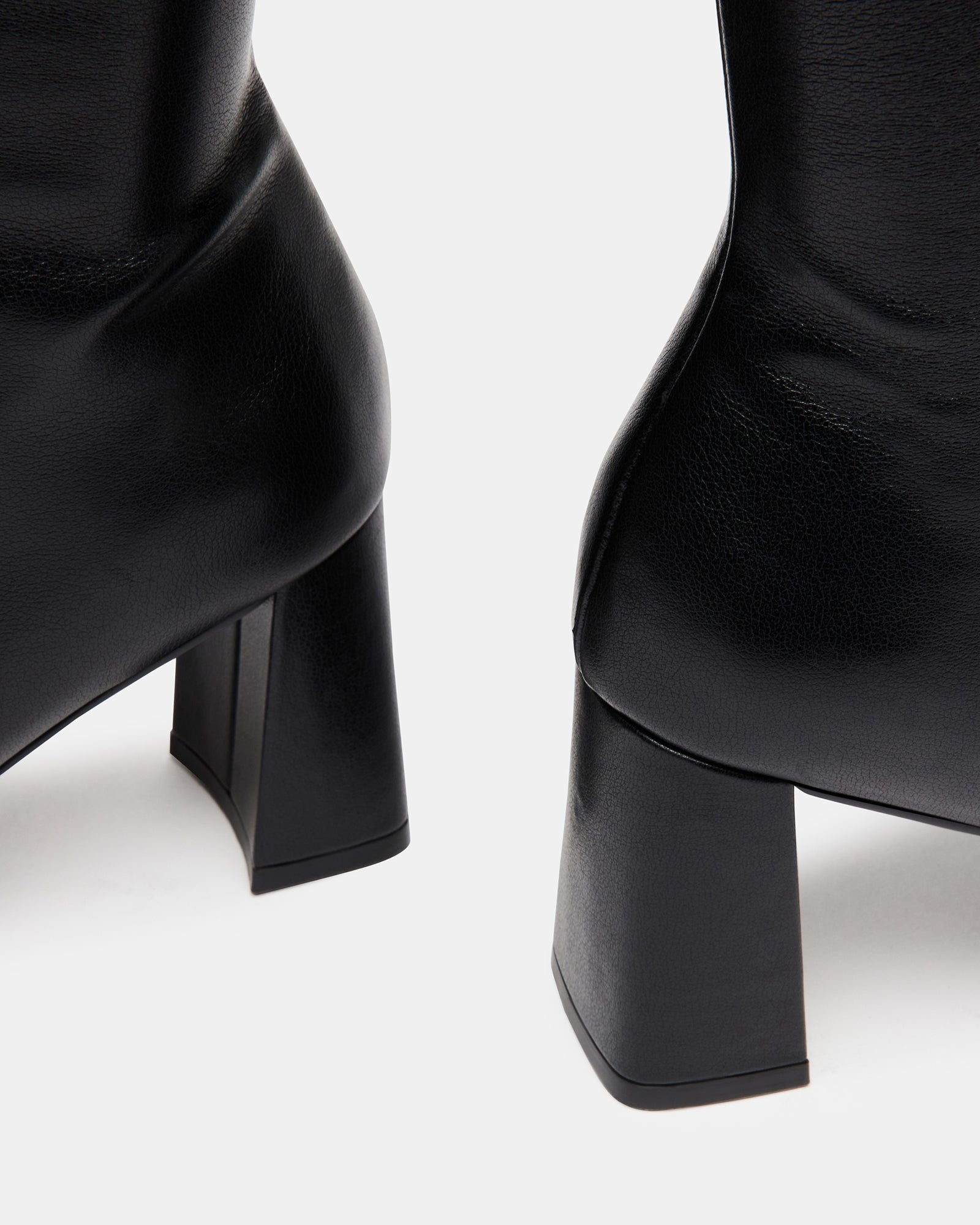 Front view of black block heel ankle boots styled with a wool coat on a New York sidewalk.
