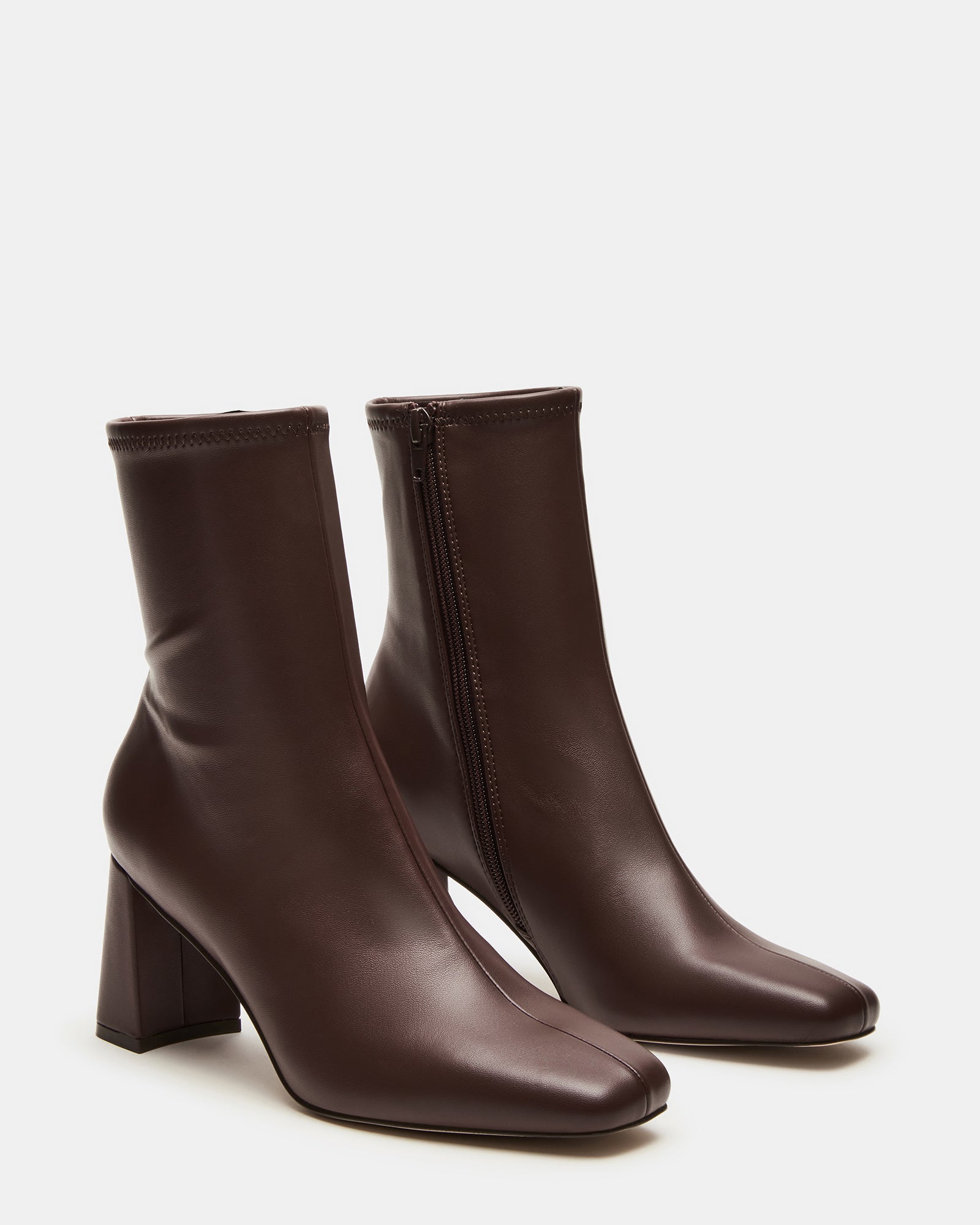 Close-up of heel and vegan leather texture on brown ankle boots indoors.