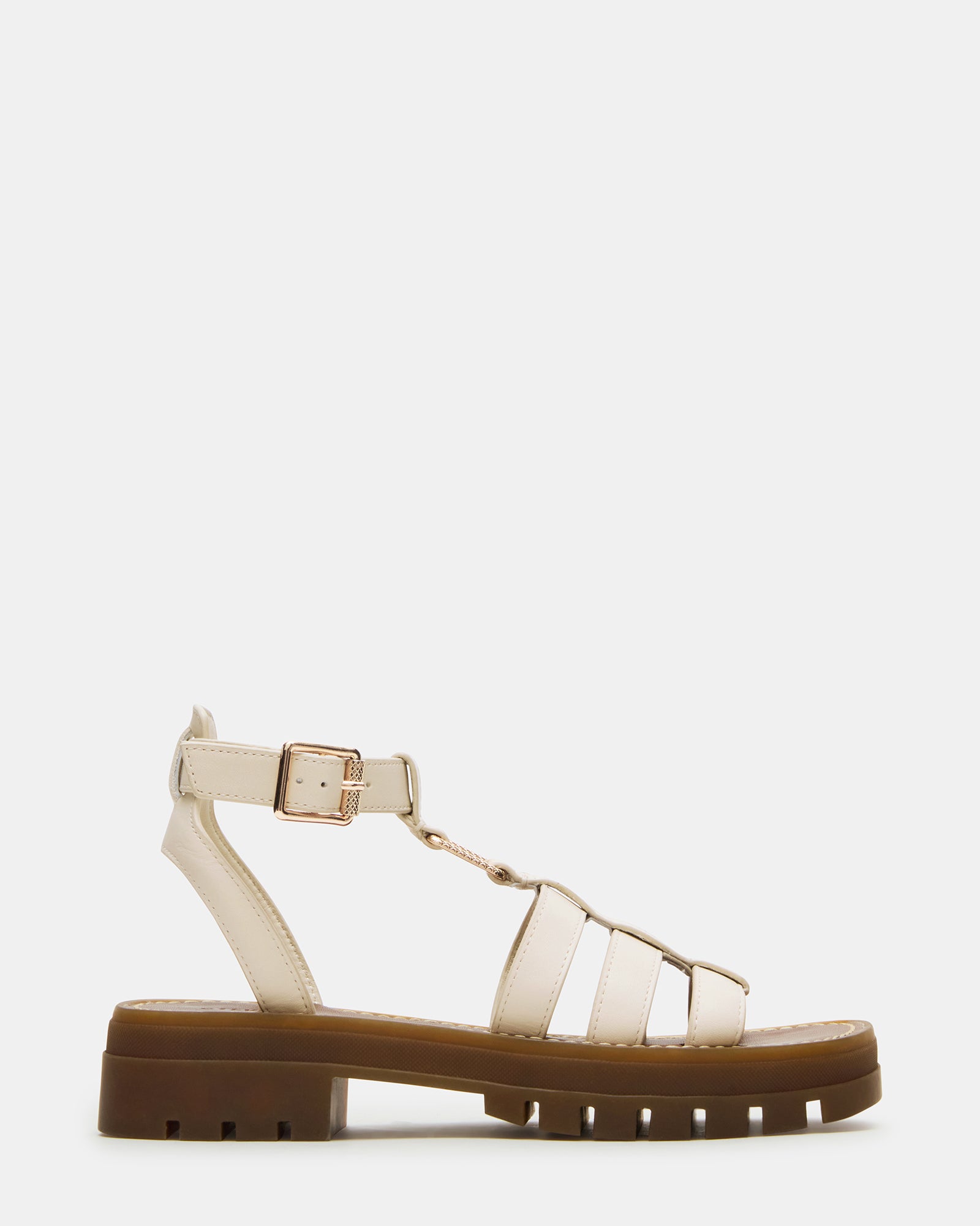 Side view of white platform sandals with bone leather straps on a summer patio