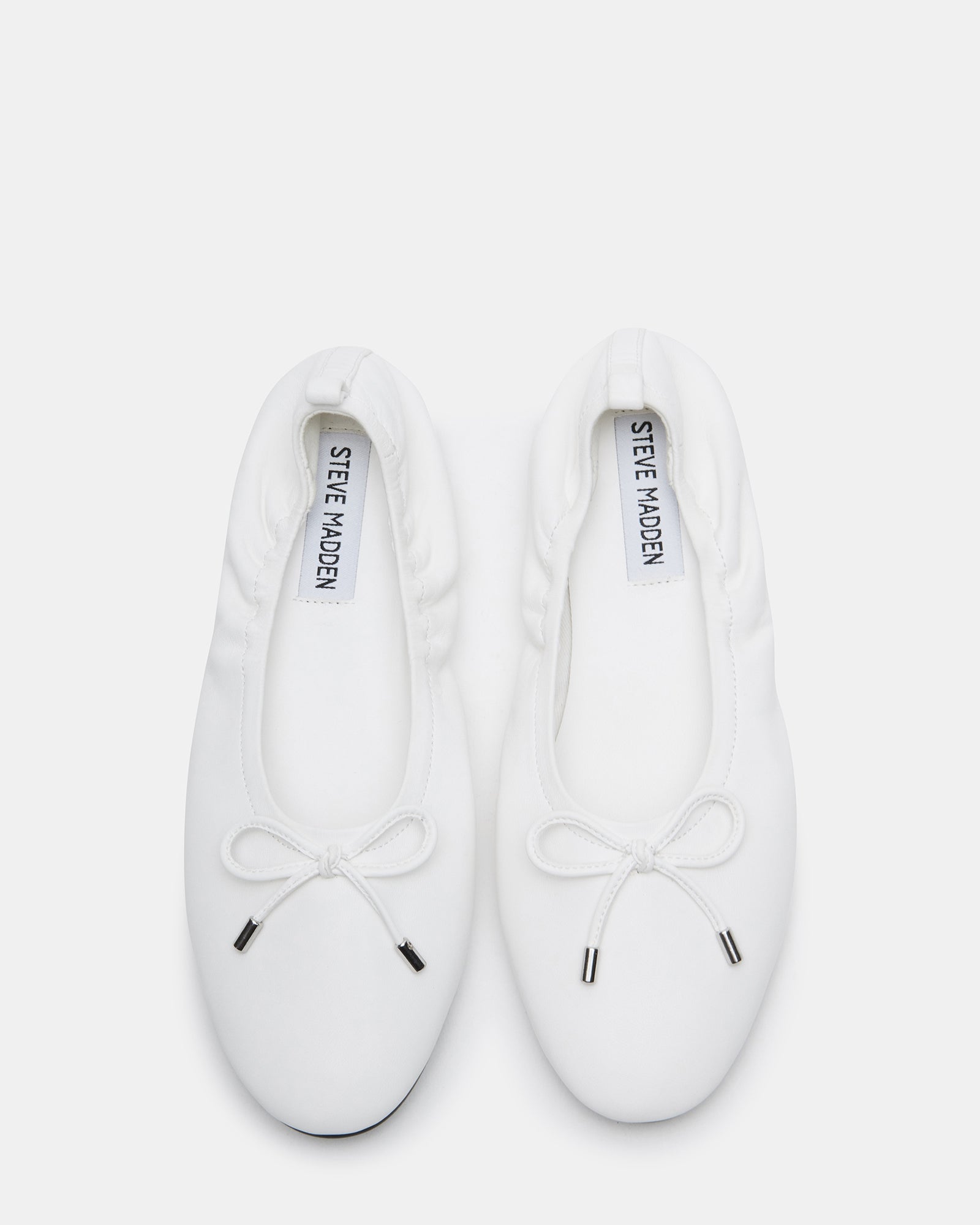 Close-up of elegant white leather ballet flats showcasing the delicate bow detail.