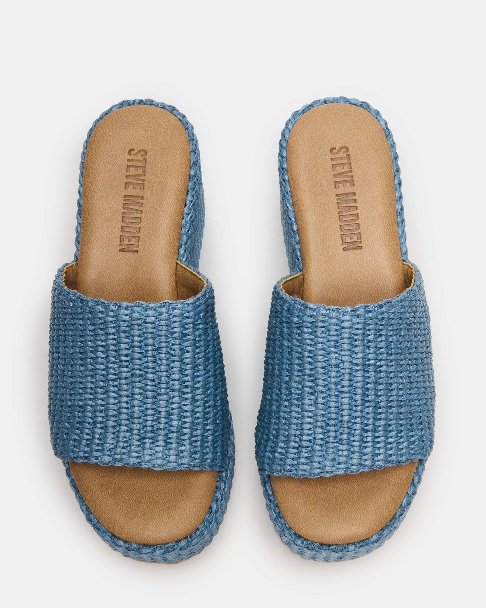 Side view of Jetty Blue raffia wedge sandals on a sunny patio.