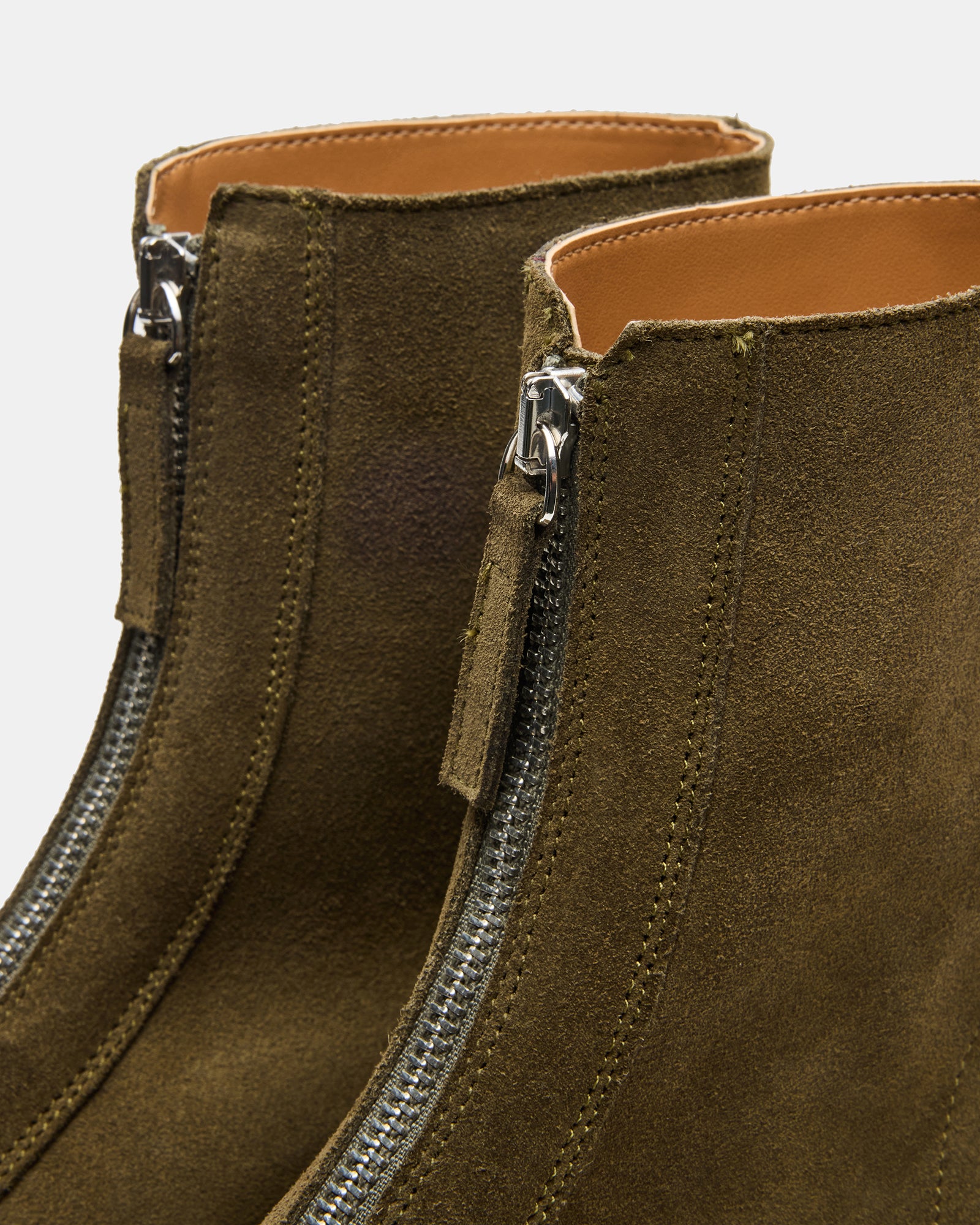 Olive suede ankle boots showcasing their stylish zipper detail.