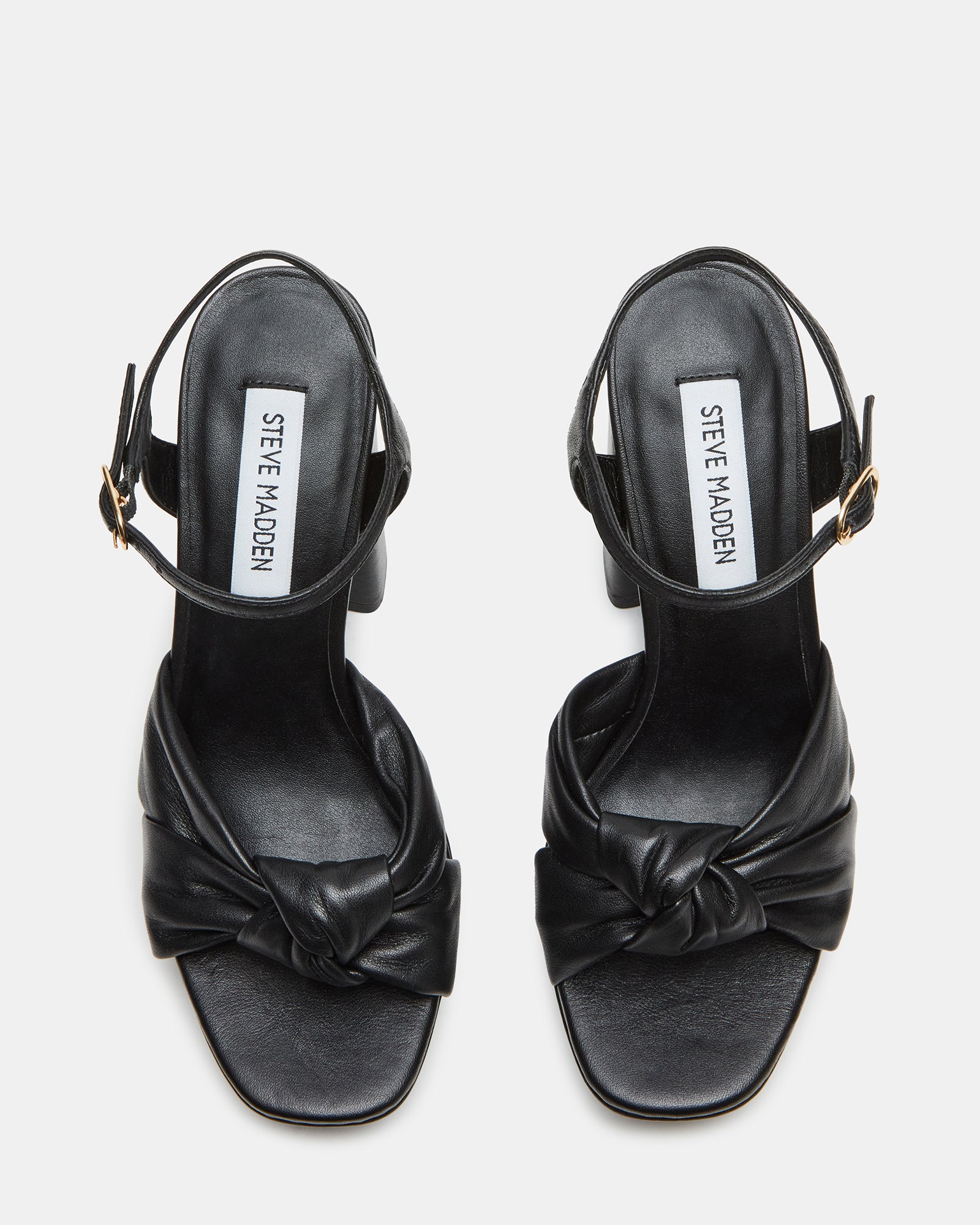 Side view of black patent leather shoes with bow detail on ankle strap
