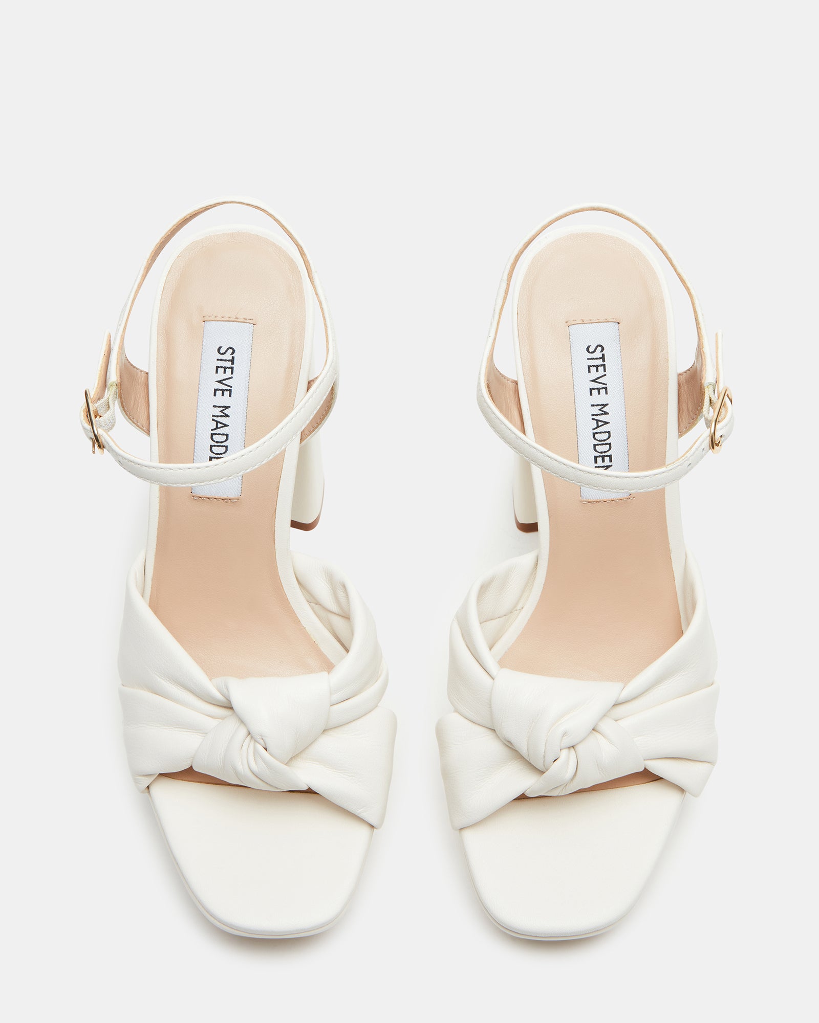 Close-up of leather heels with bow detail and ankle strap.