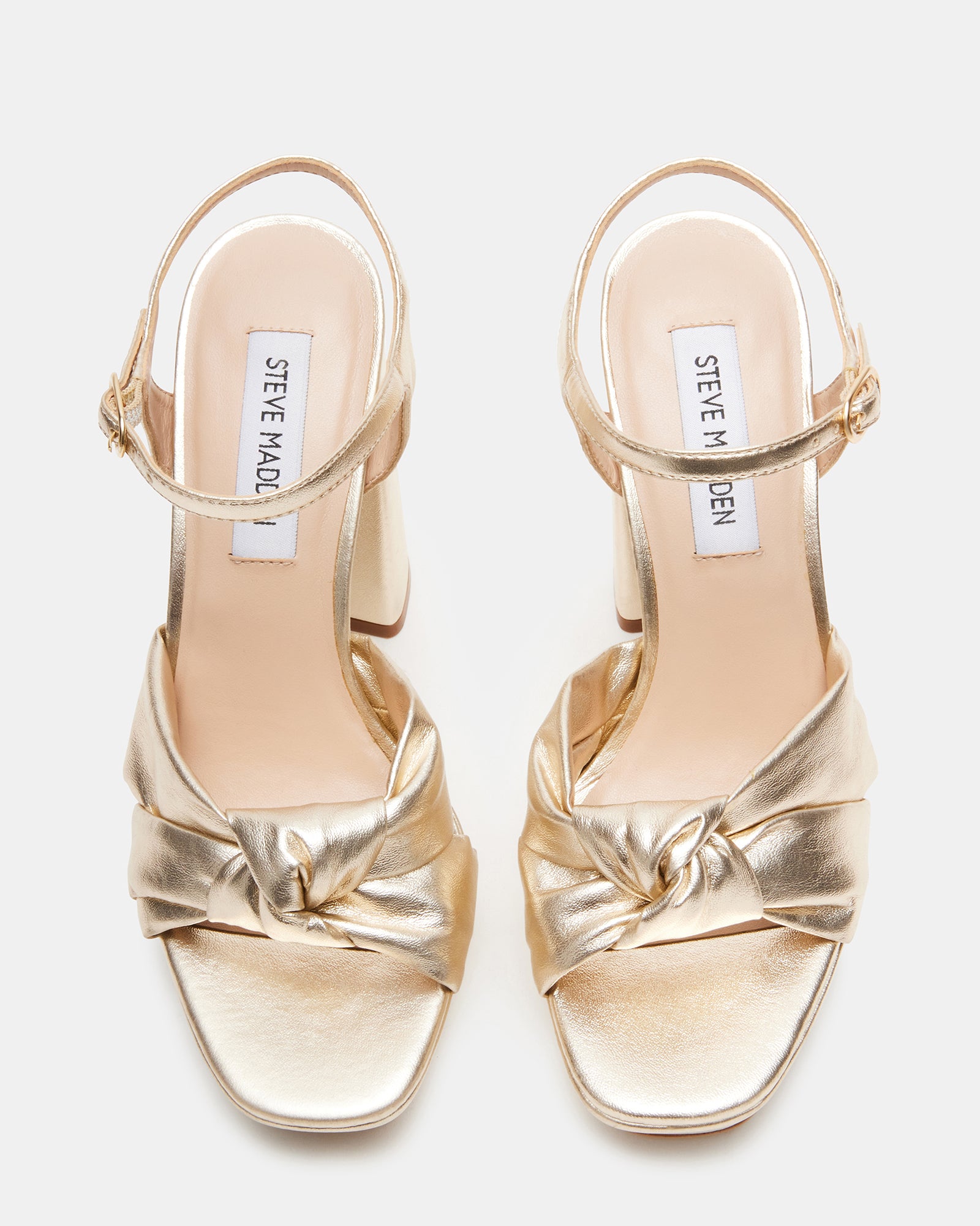 Close-up of champagne platform shoes with bow detail.