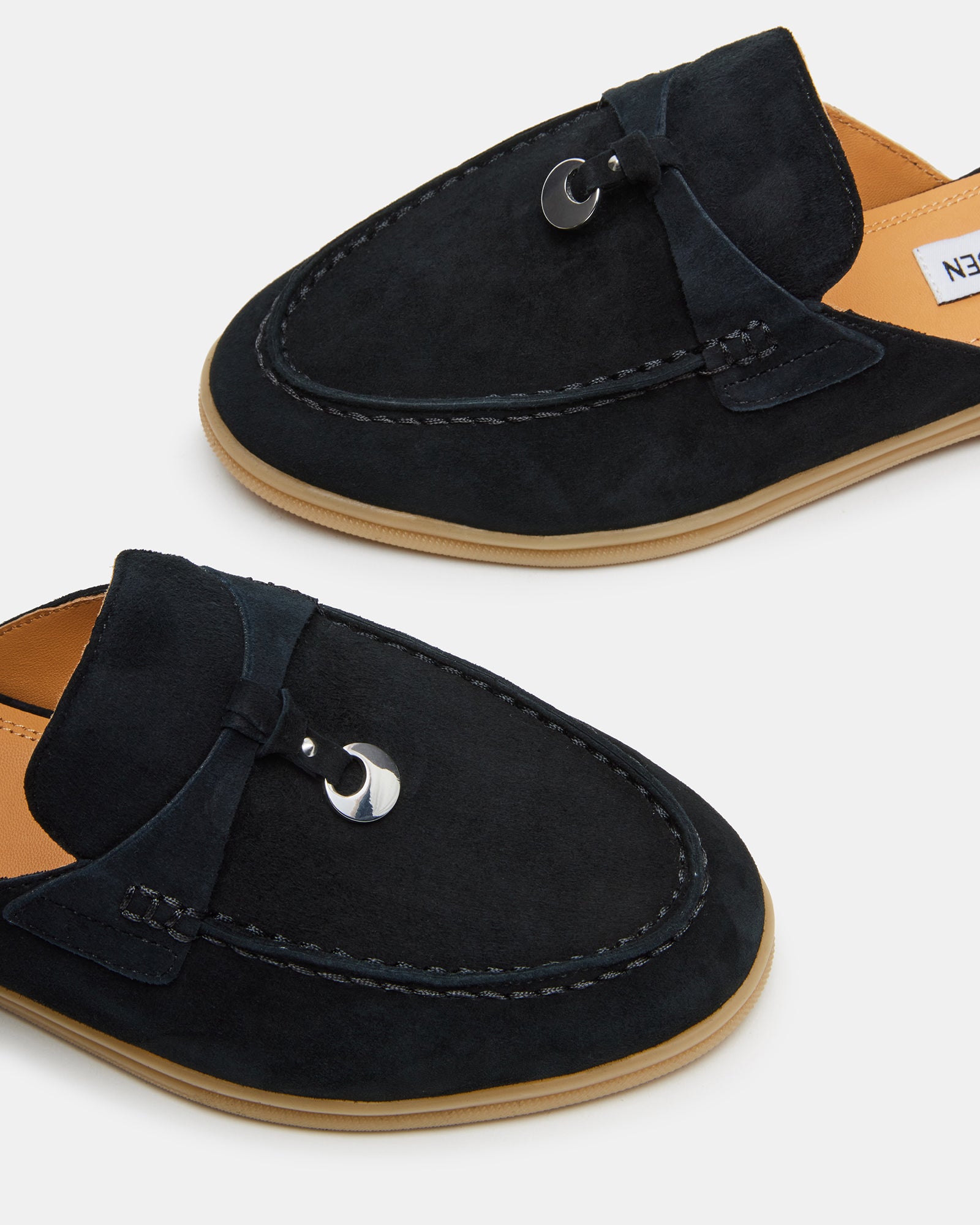 Lifestyle shot of suede flats styled with cropped denim near a Louisiana café