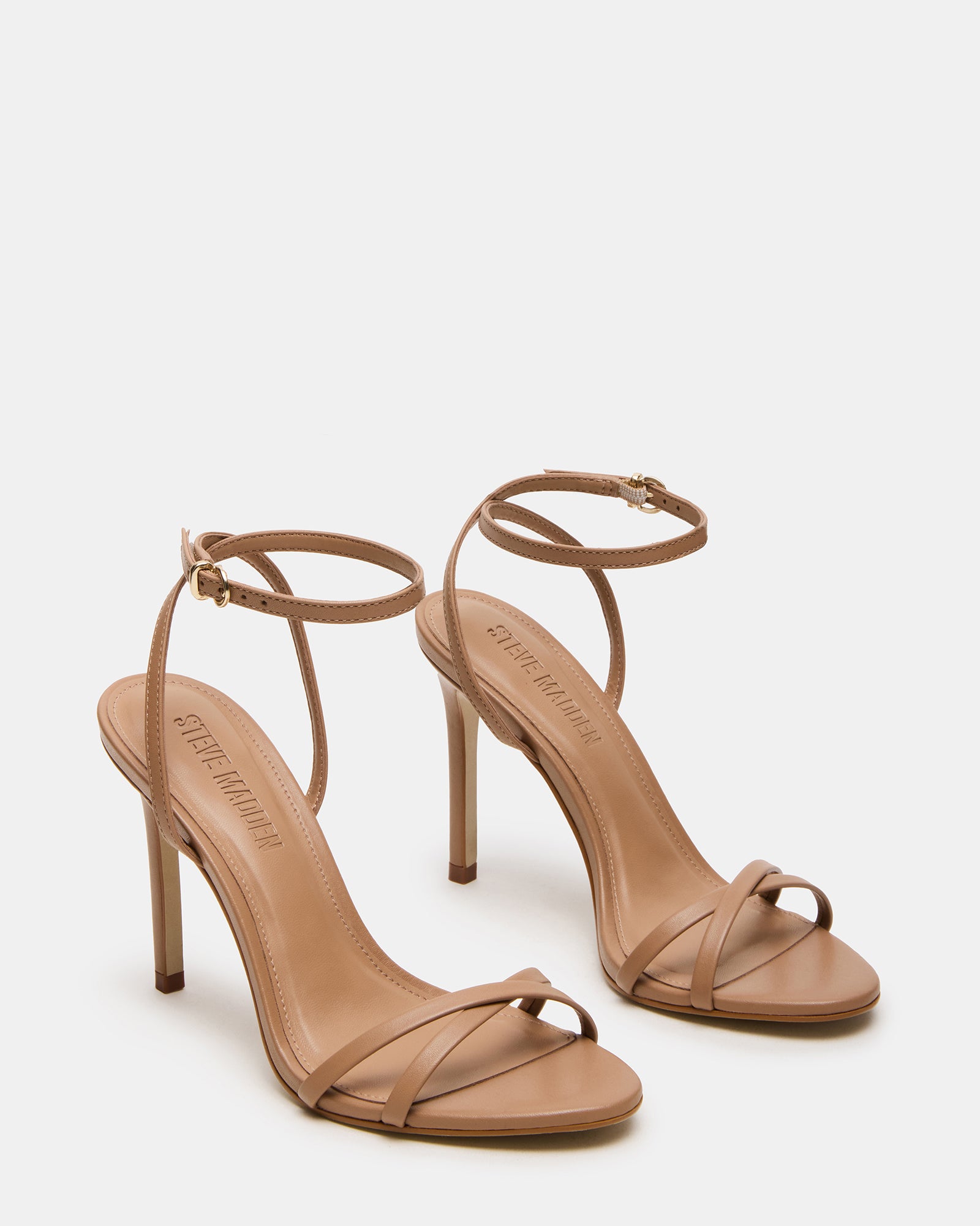Close-up of the rounded toe and crisscross back of the tan stiletto heels.