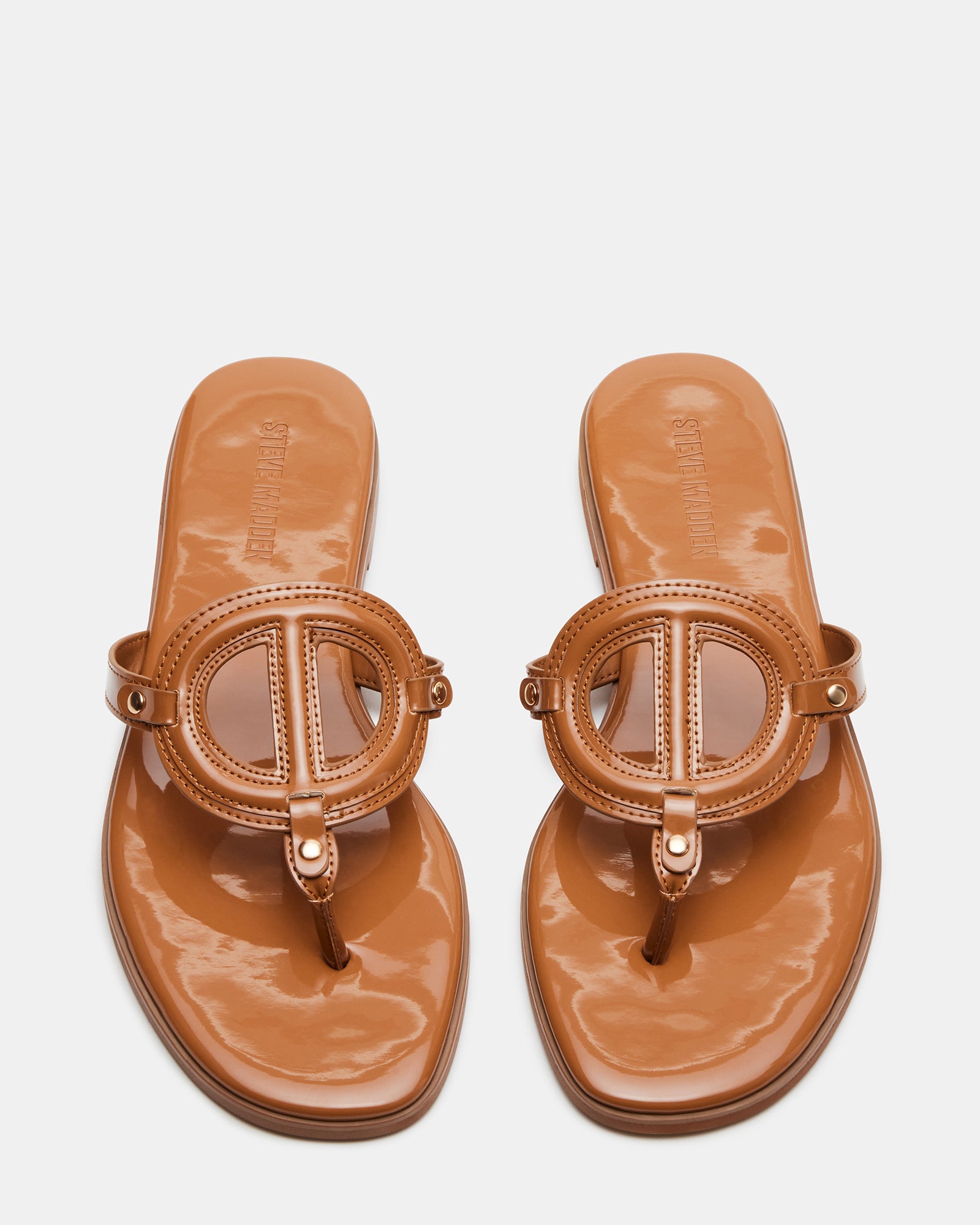 Top-down view of tan black thong sandals with patent finish and low heel