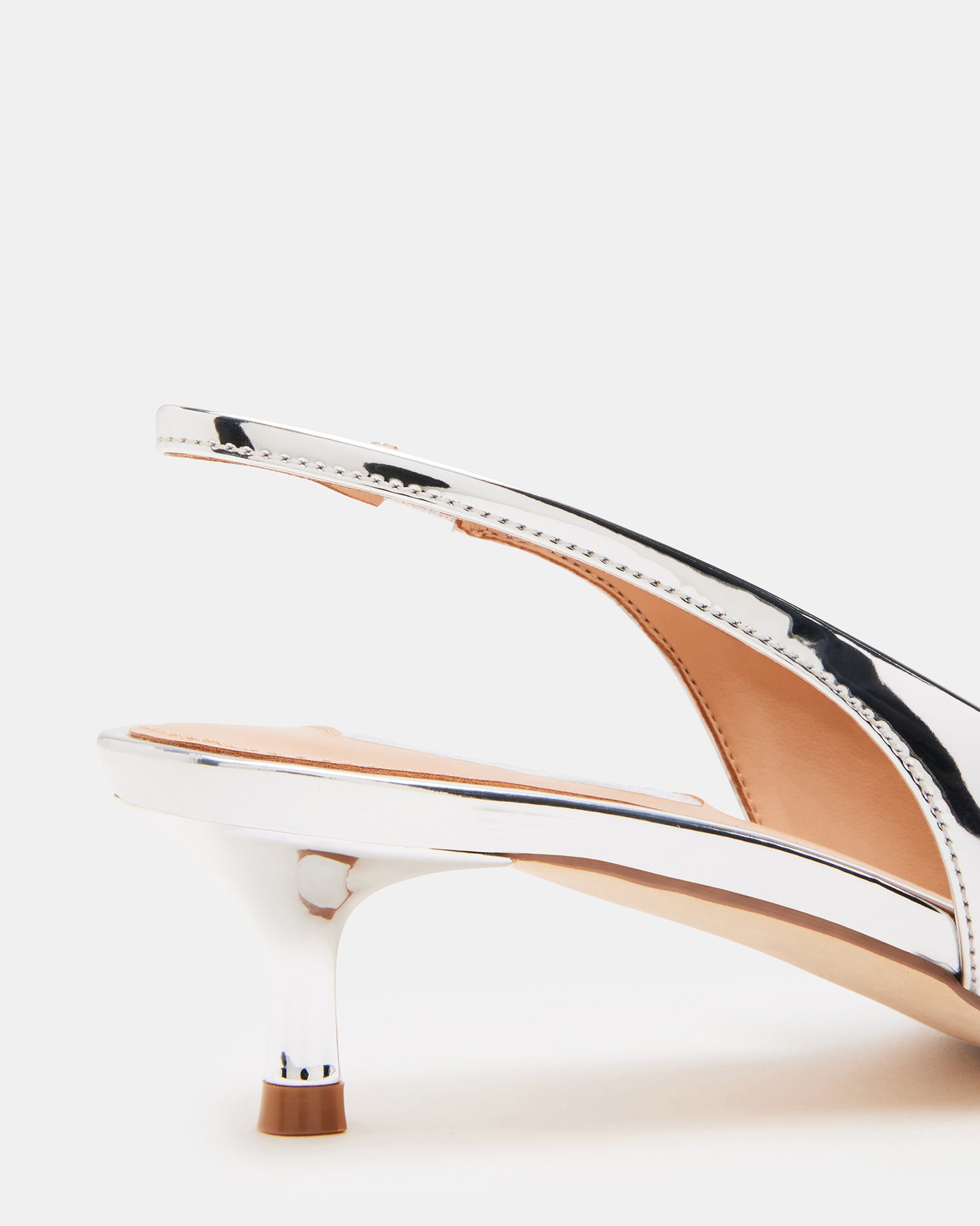 Side view of Kari silver slingback kitten heels with pointed toe detail on model outdoors