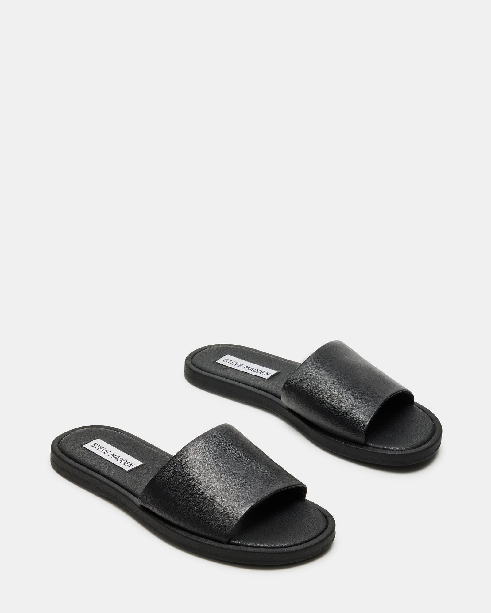 Kaya black leather sandals worn casually in an outdoor setting.