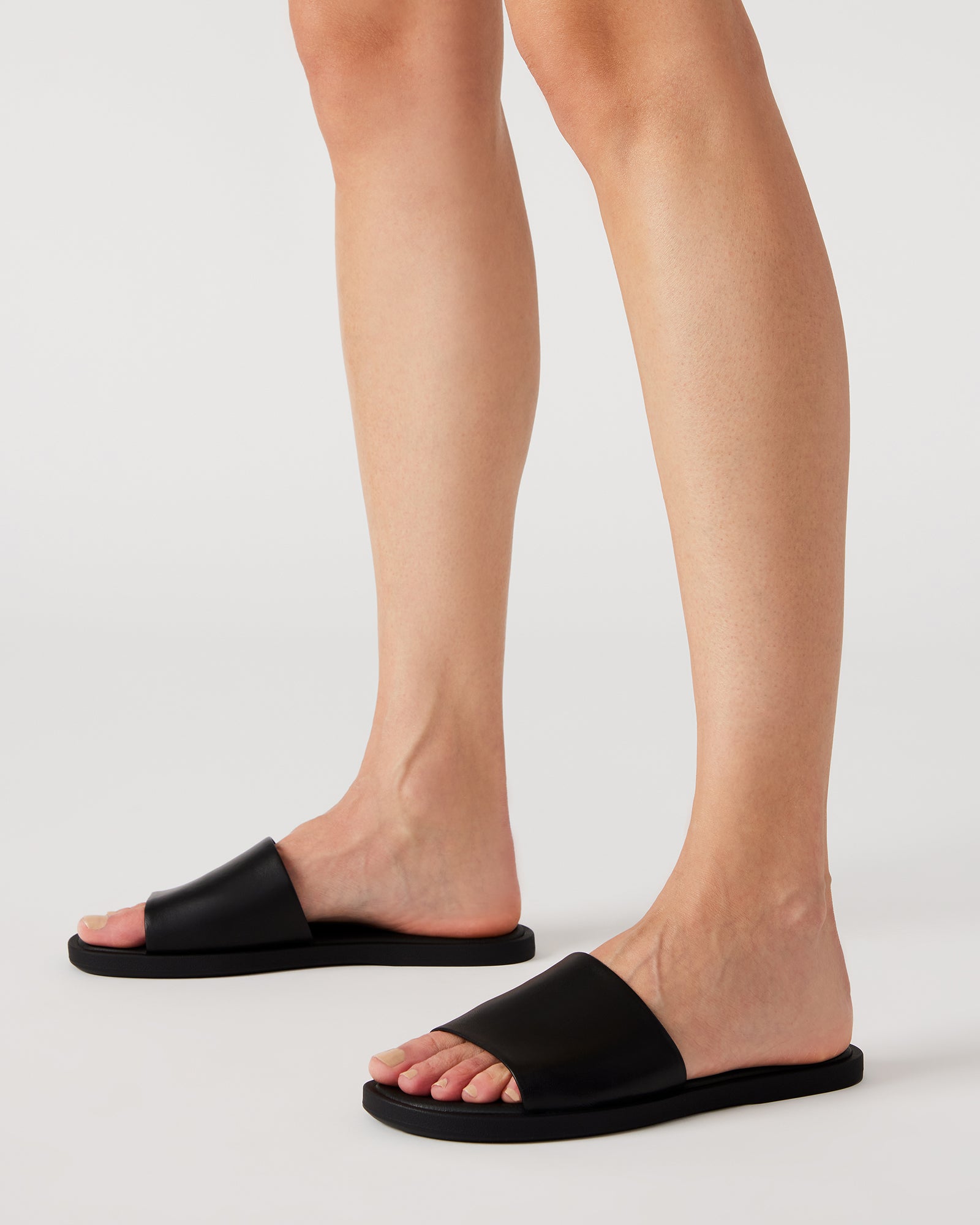 Close-up of the wide strap on Kaya black leather slide sandals.
