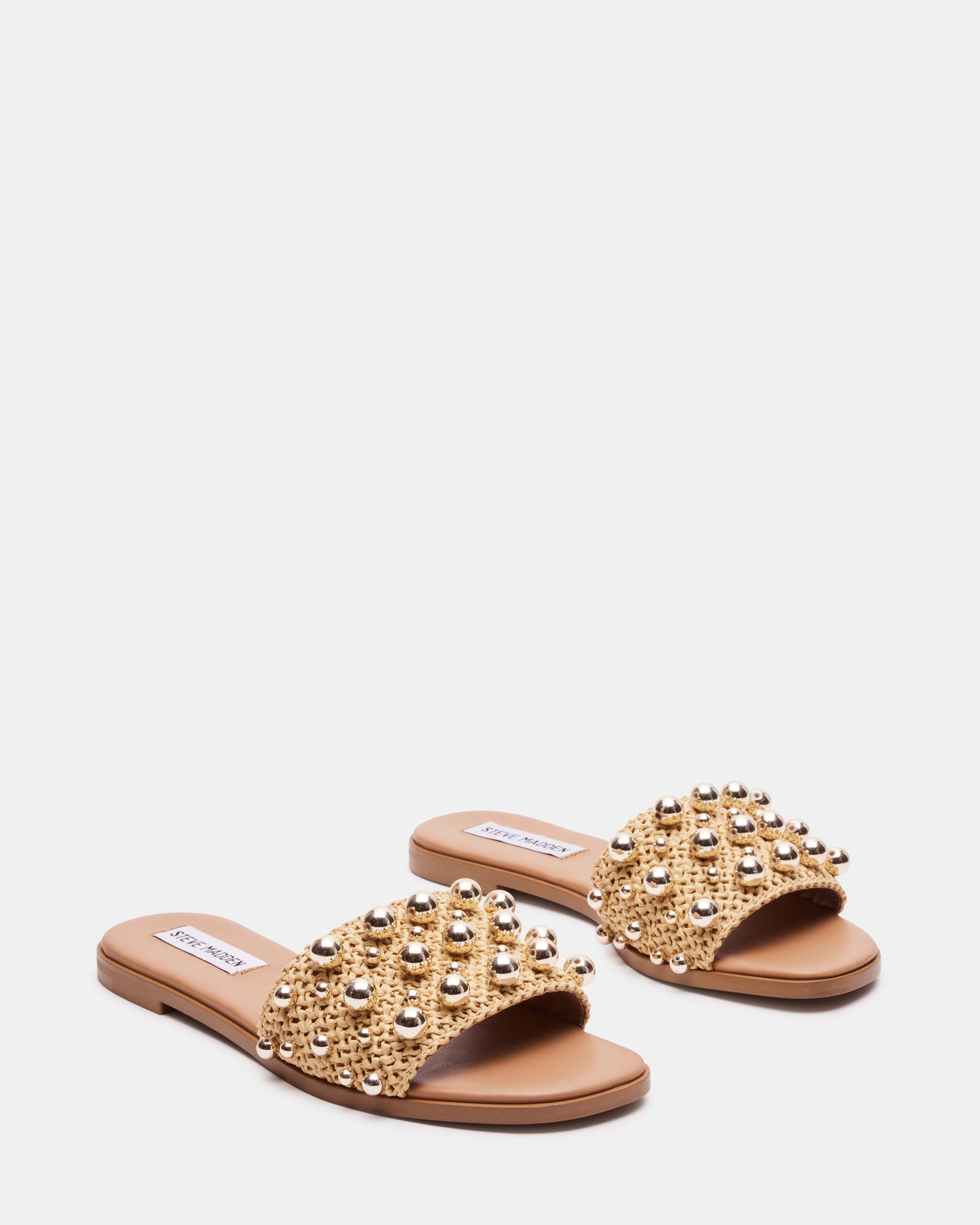 Lifestyle shot of raffia sandals worn at a sunny beach setting.