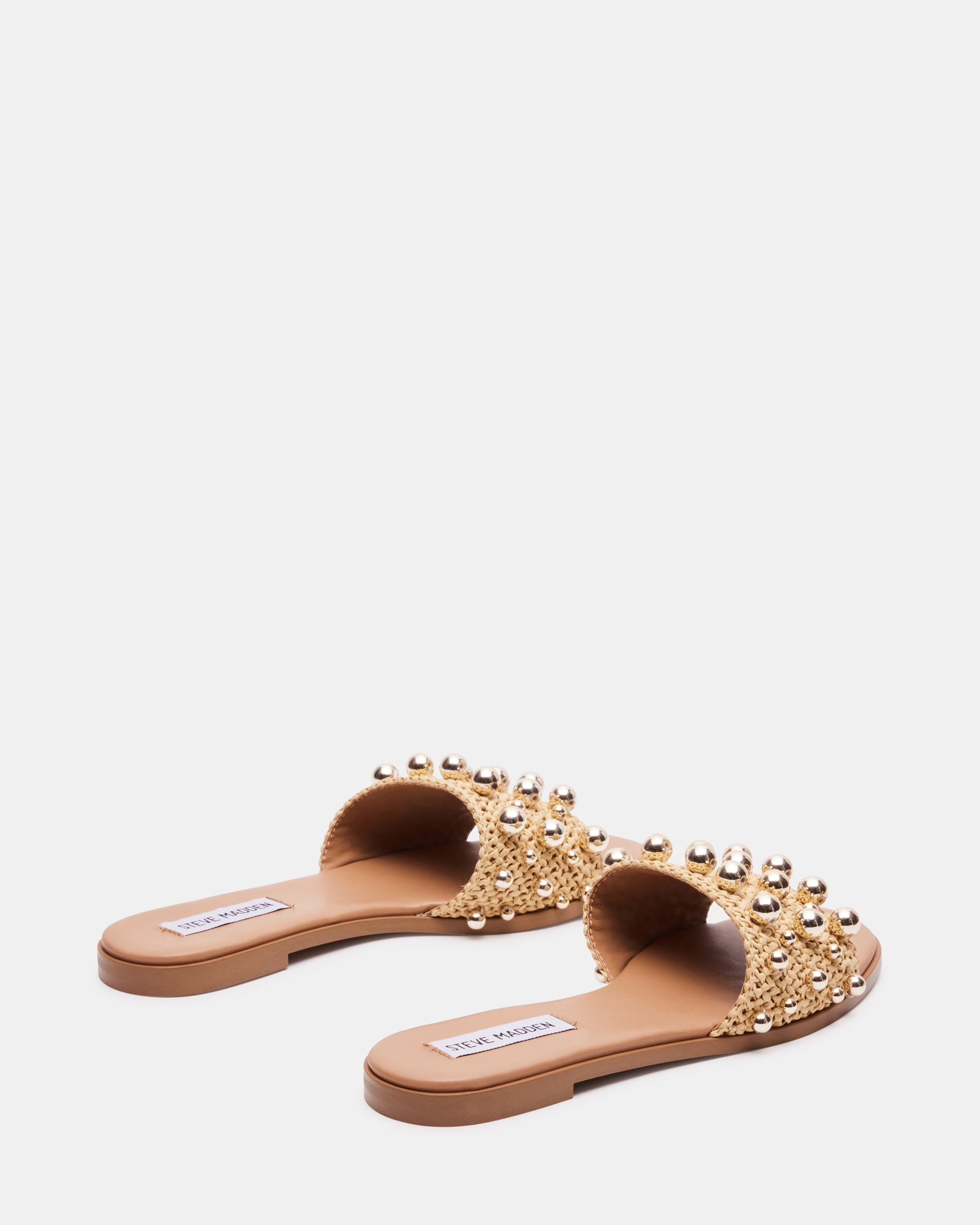 Lifestyle shot of raffia sandals worn at a sunny beach setting.