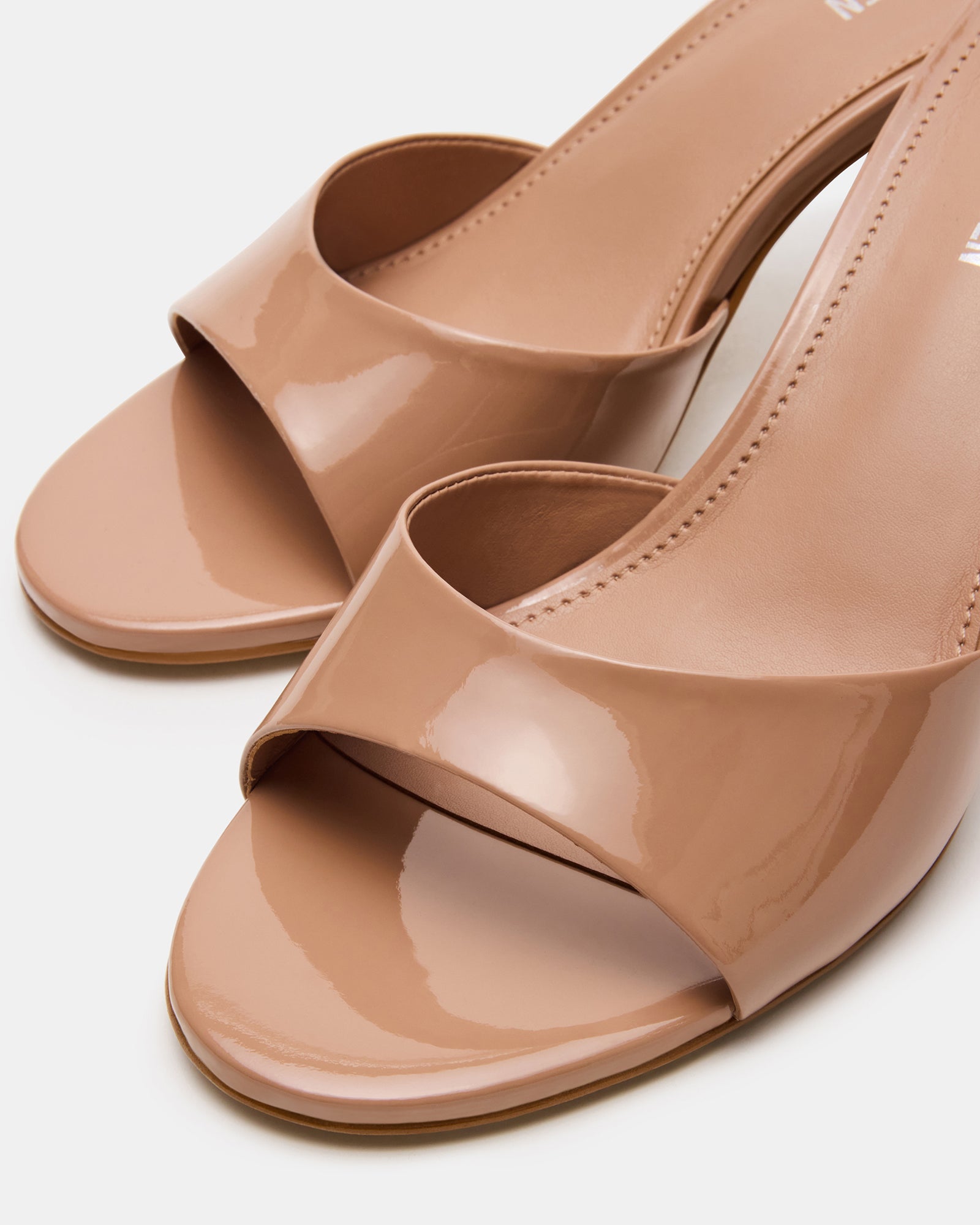 Blush leather mule heels with rounded toe and patent finish, showcased on a models feet.