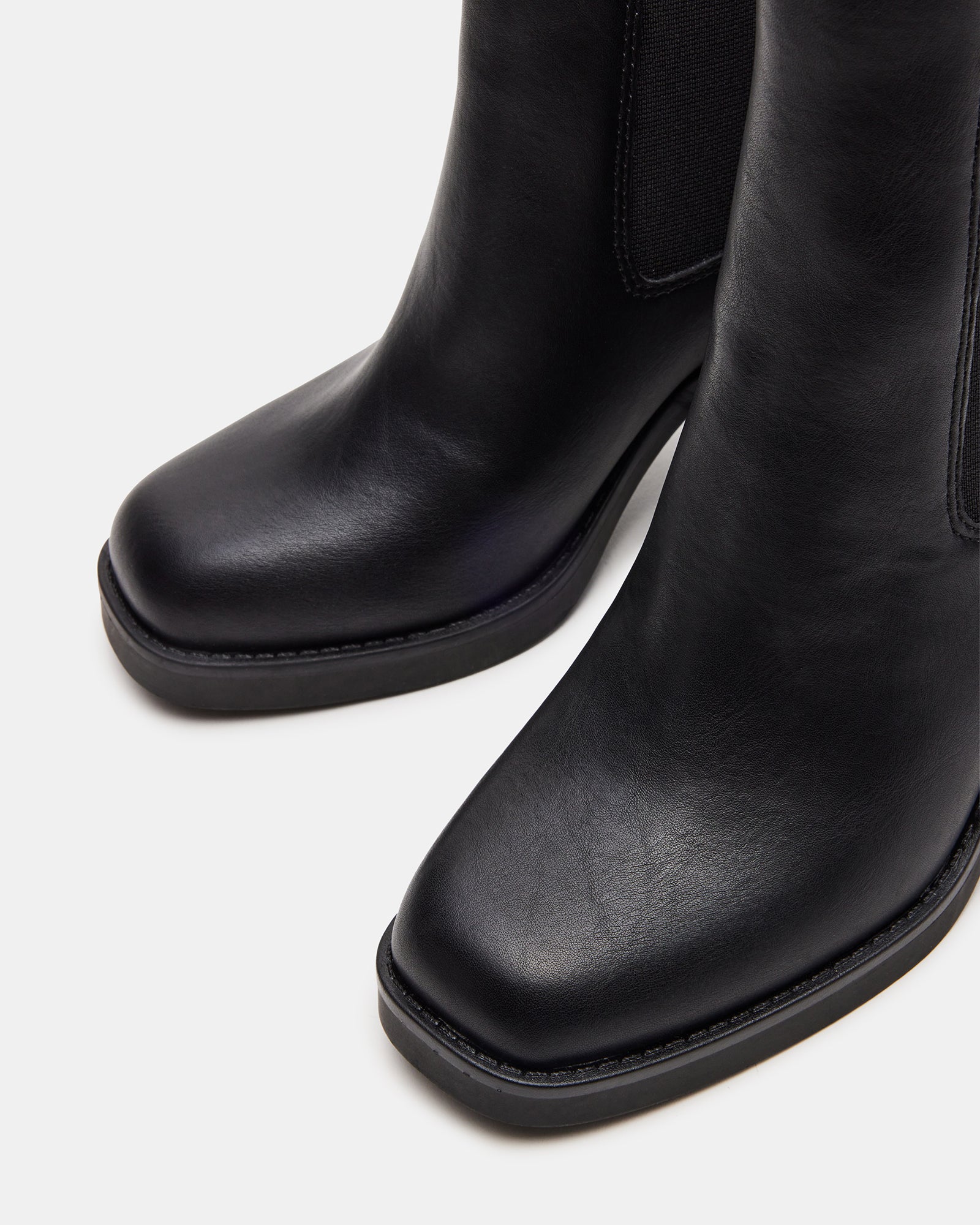Side view of black ankle boots styled with denim for city wear