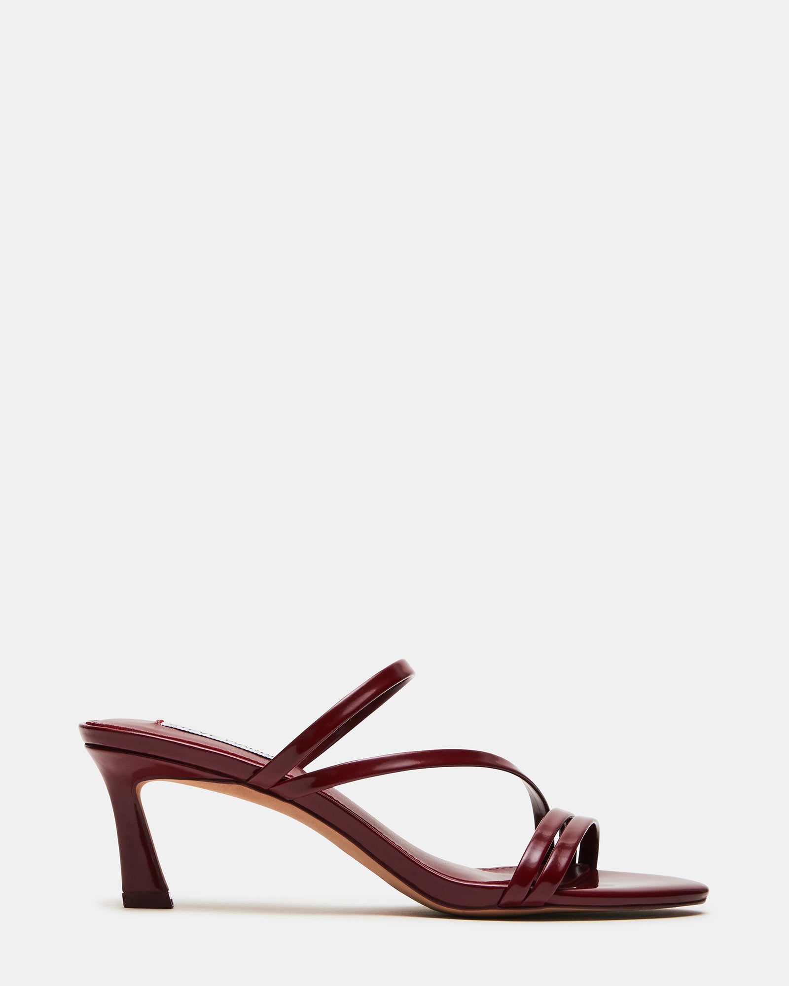 Side view of black patent leather heels styled with a minimalist outfit.