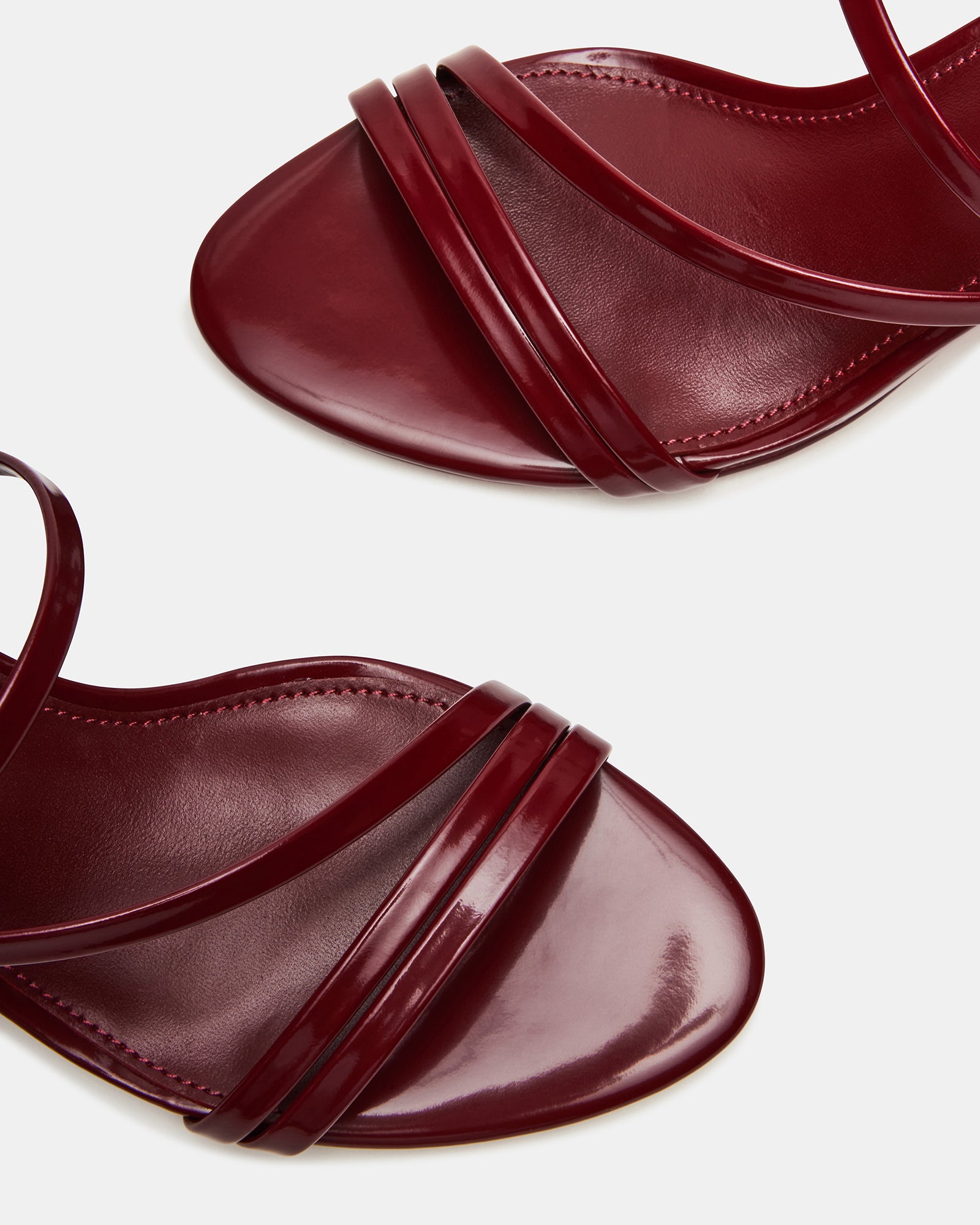 Side view of black patent leather heels styled with a minimalist outfit.