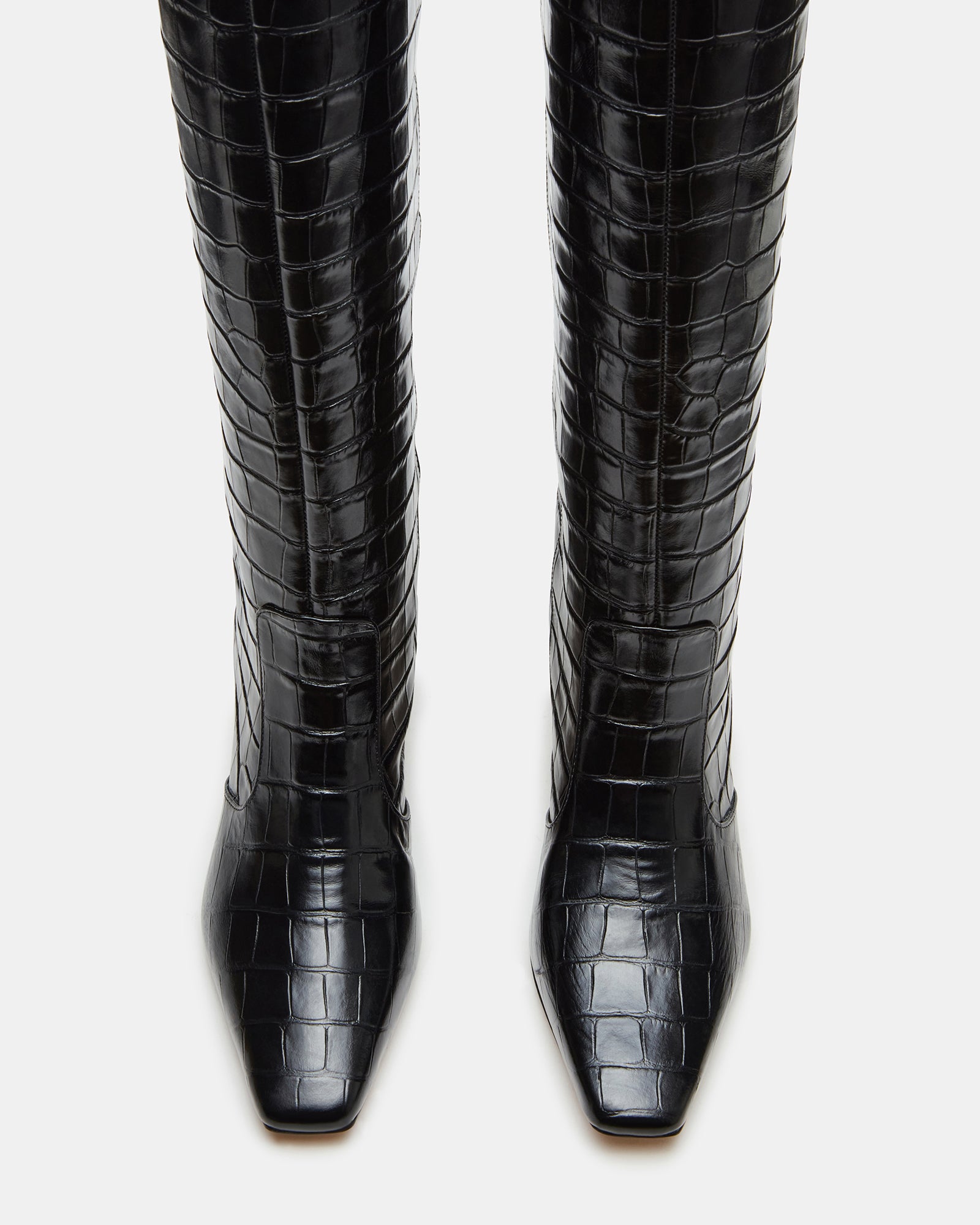 Close-up of the black crocodile texture on knee high boots.