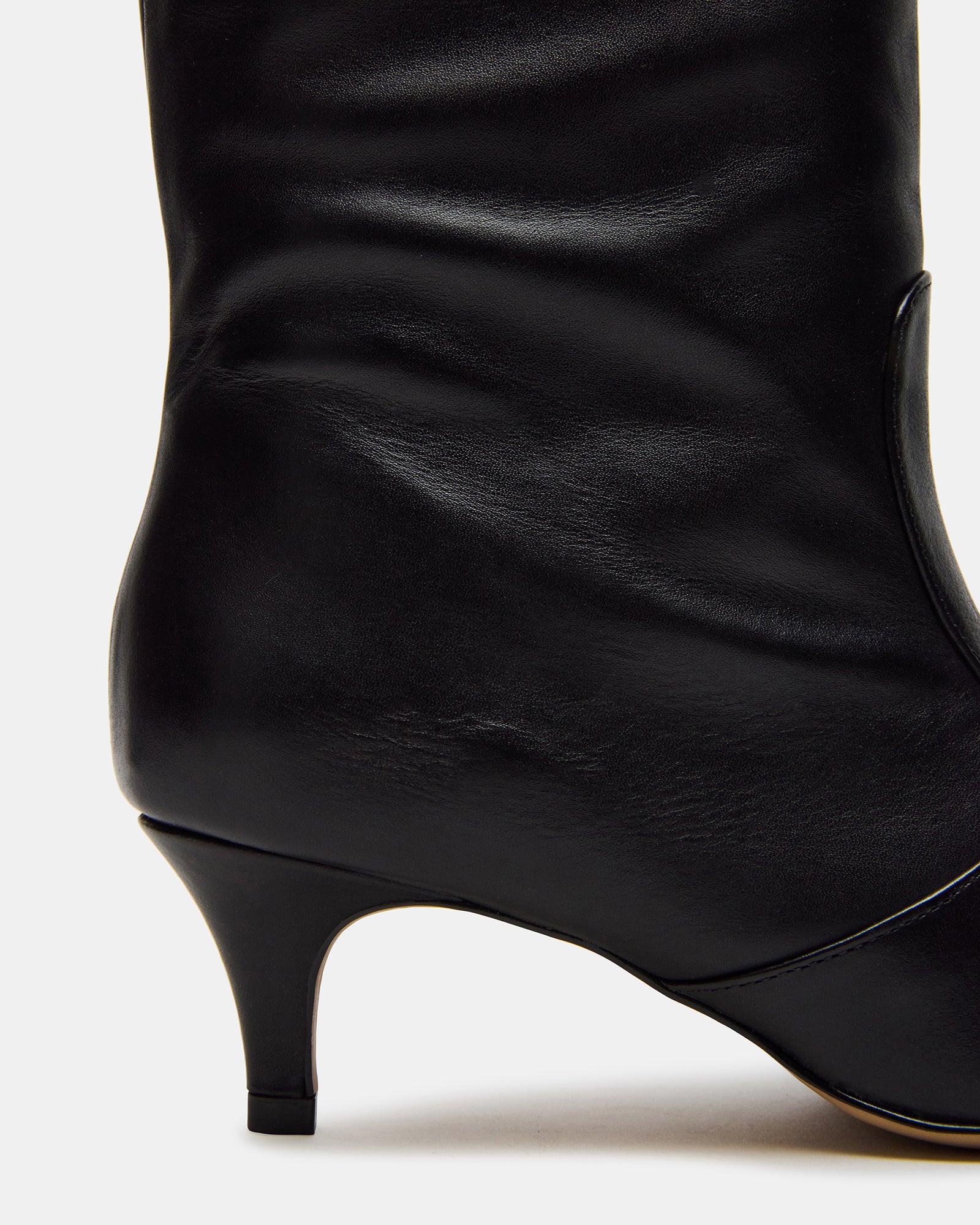 Black leather knee-high boots from the side, showcasing the kitten heel.