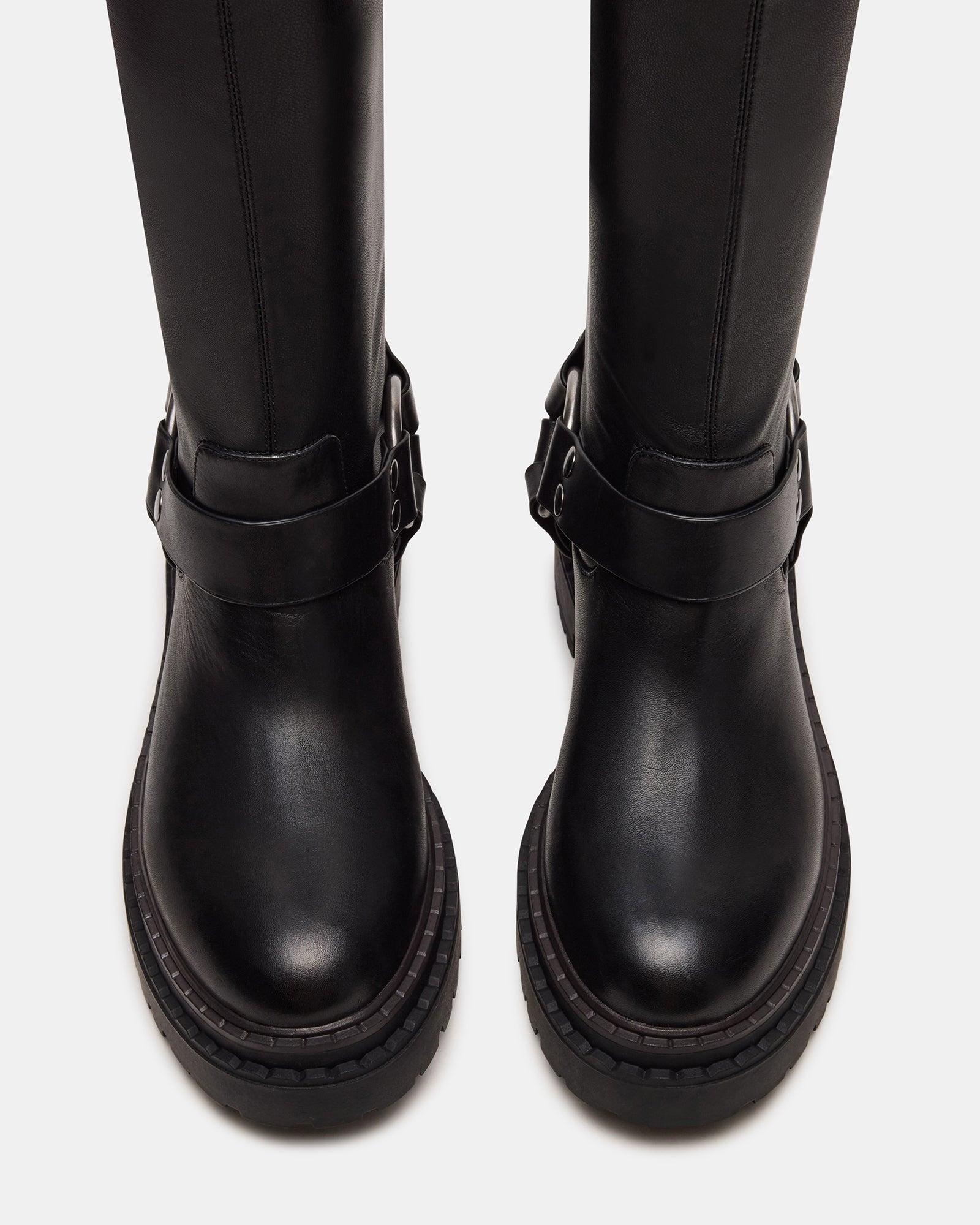 Front angle of black over the knee boots styled with denim on urban steps