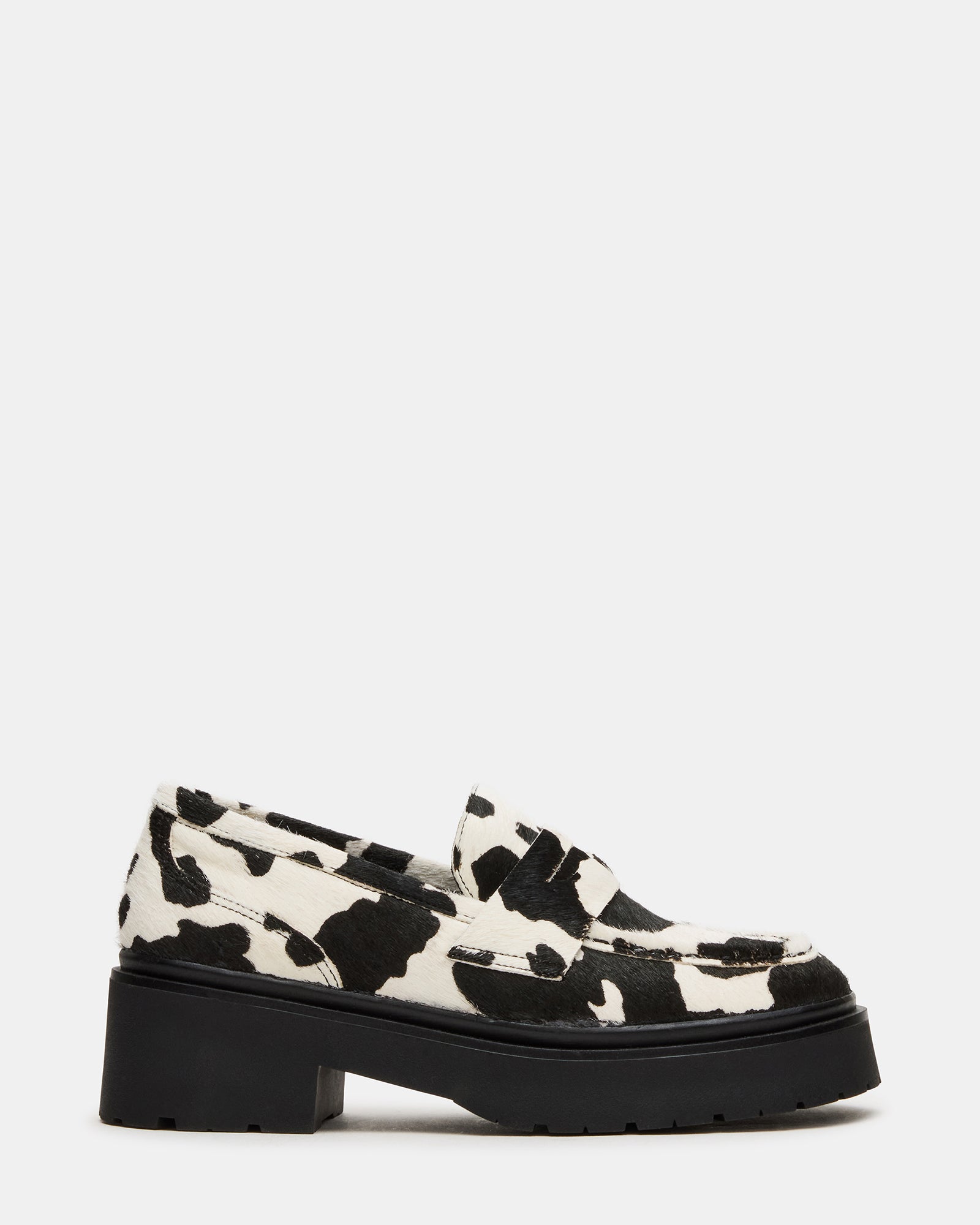 Side view of black platform loafers with cow-print detail, highlighting lug sole