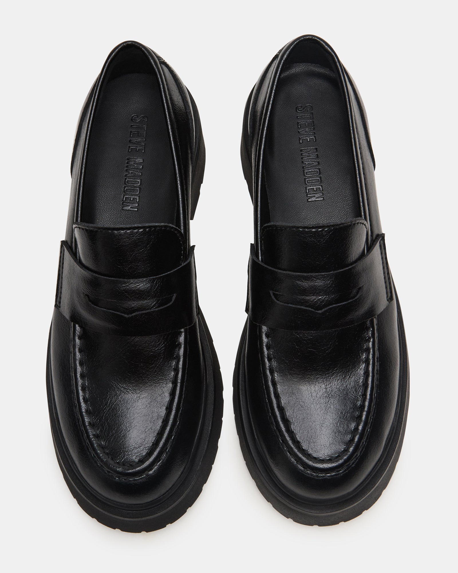 Side view of black leather loafers with lug sole on a city street