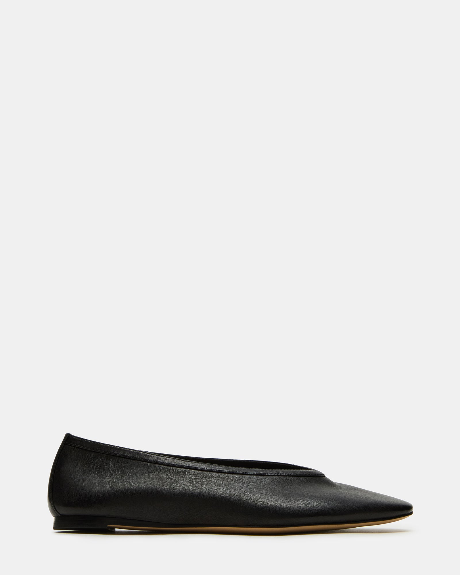 Side view of black leather square toe ballet flats on a wooden floor.