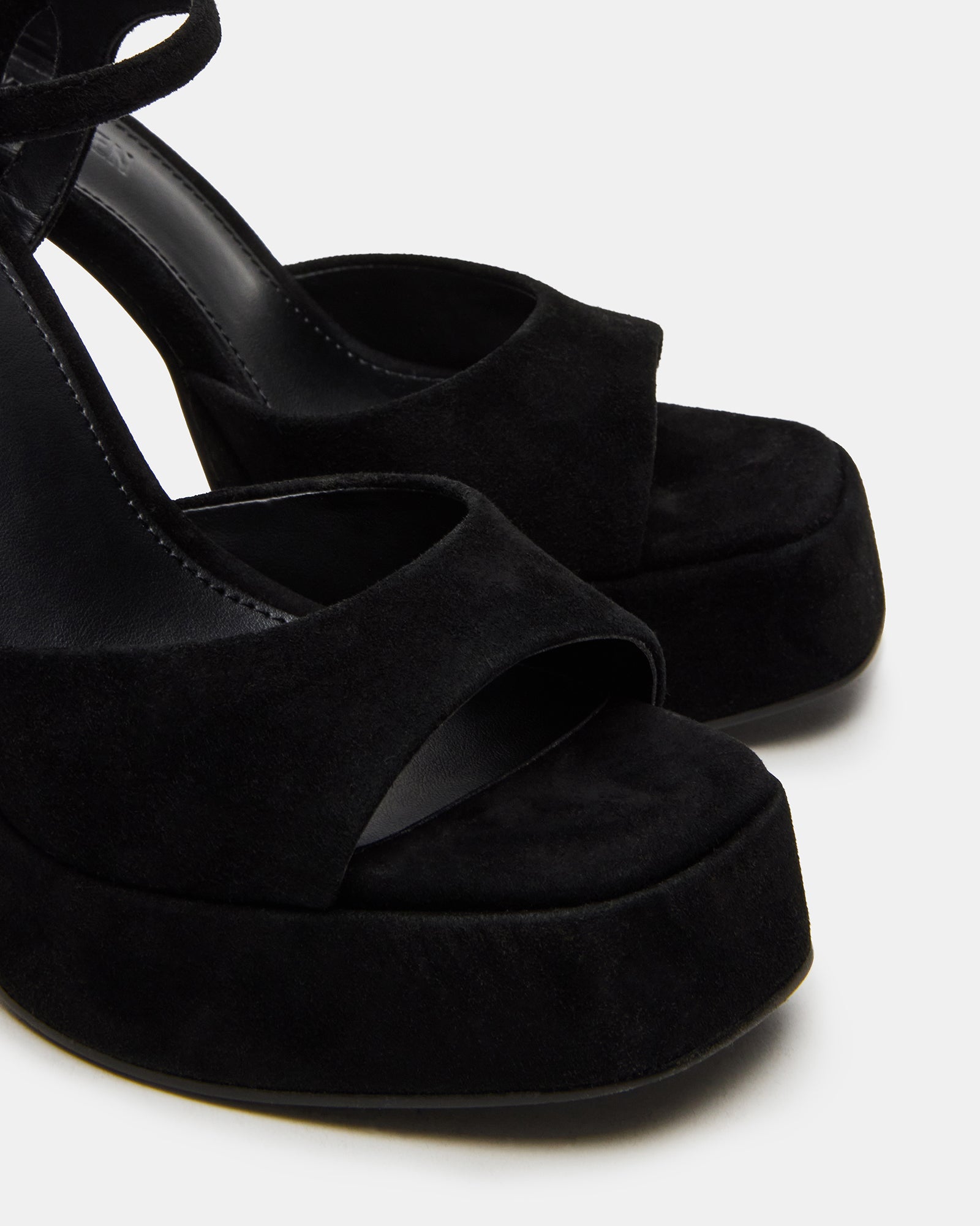 Side view of black suede platform shoes with block heels, styled for city wear.