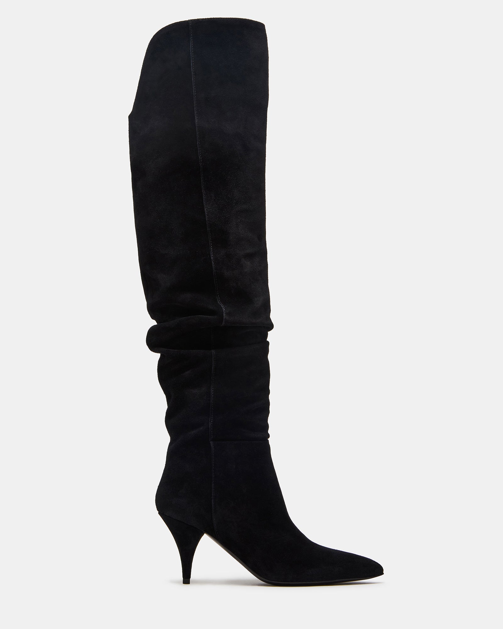 Side view of pointed toe black suede boots worn with a dress.