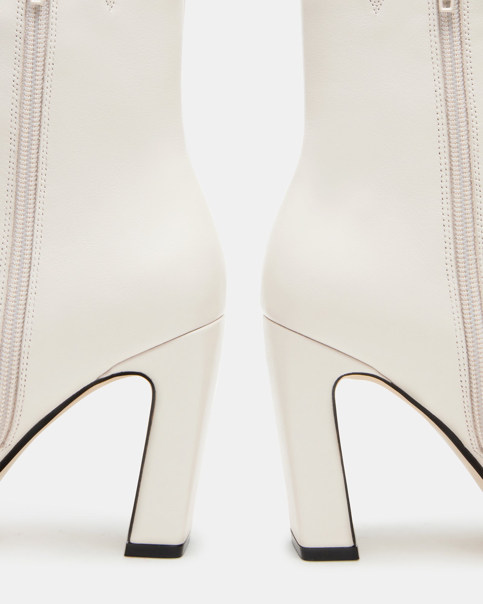 Side view of luxurious bone leather chelsea booties on a wooden floor.