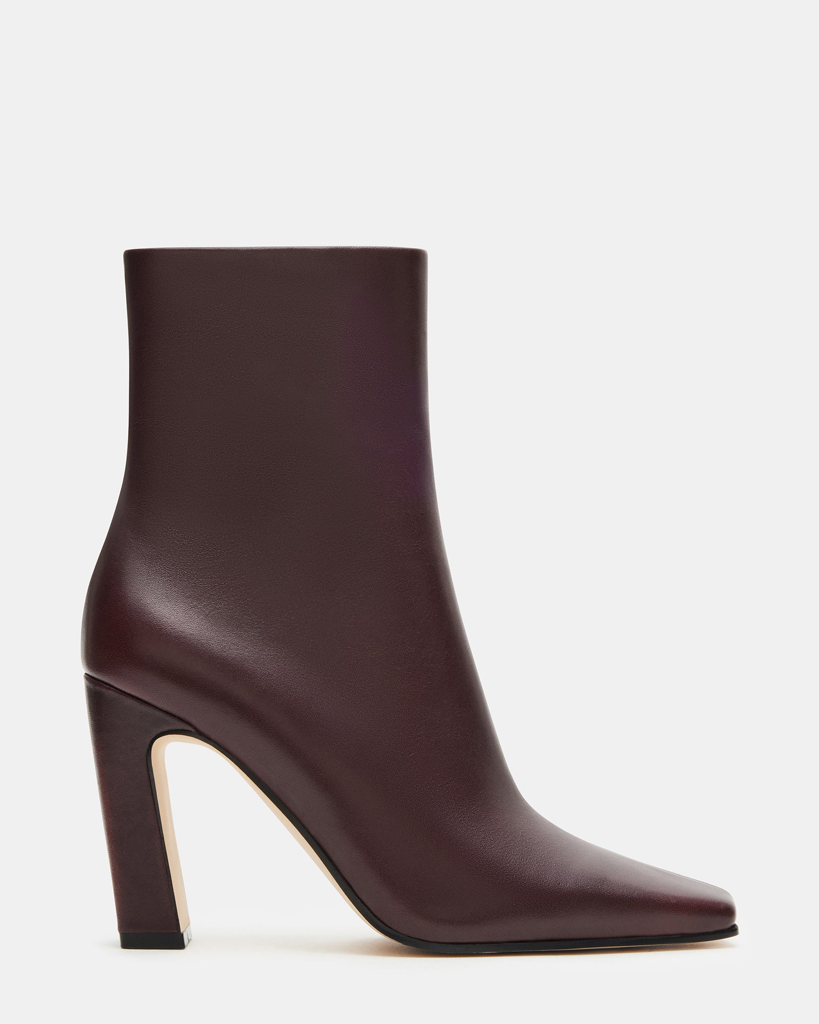 Side profile showing brown leather boots with 3.5 inch heel on urban sidewalk