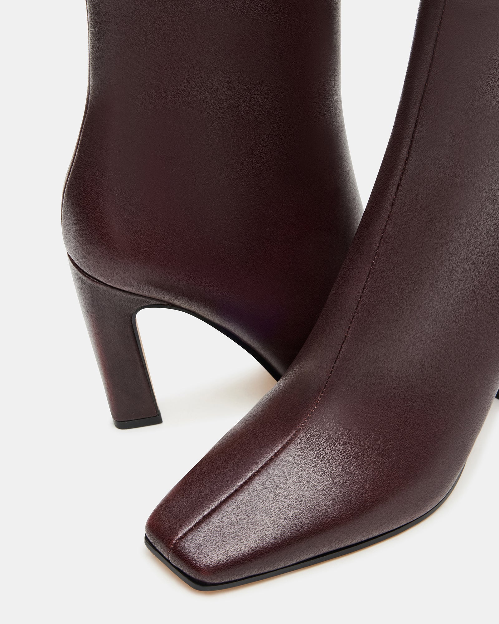 Side profile showing brown leather boots with 3.5 inch heel on urban sidewalk
