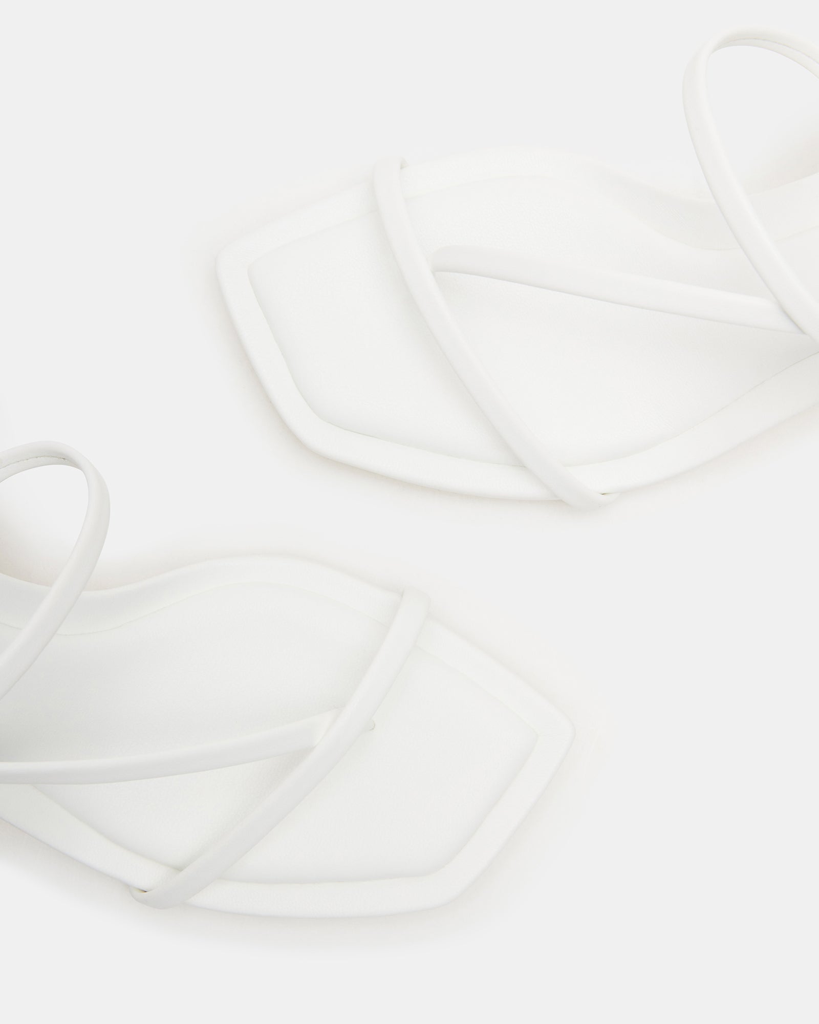 Side view of Locke White heels on hardwood floor, showcasing square toe design