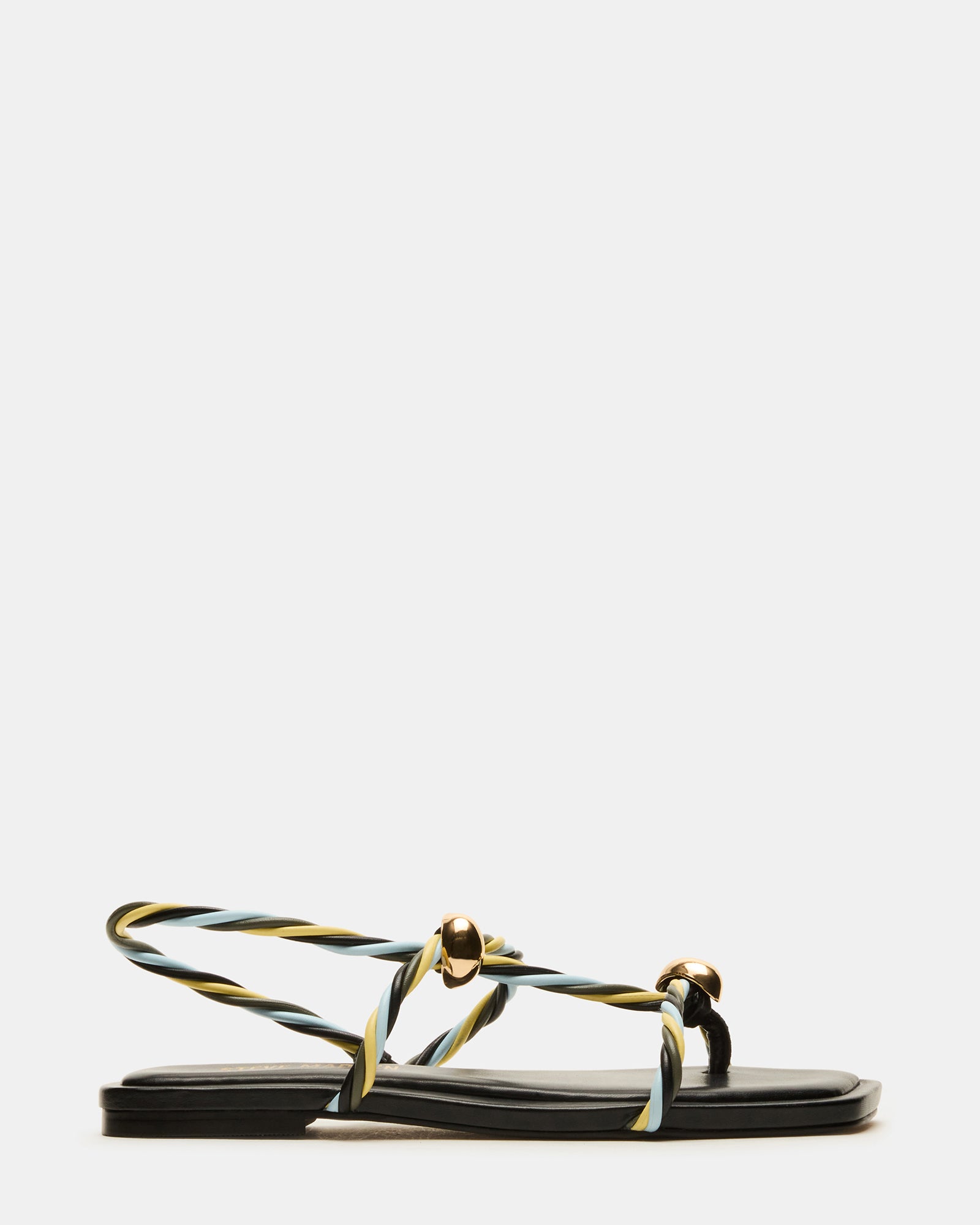 Black strappy sandals with a square toe on a model's feet in a sunny park.