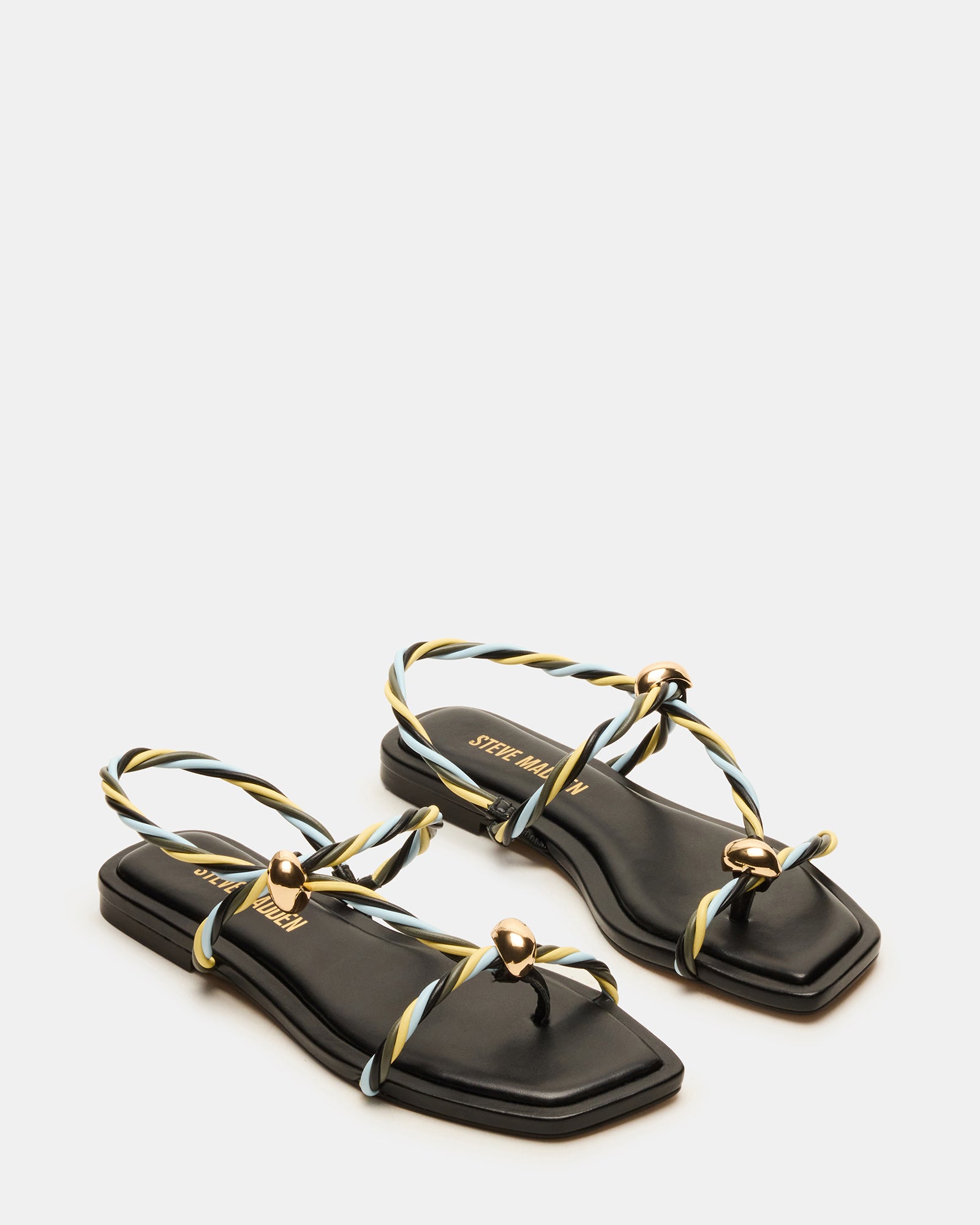 Stylish black strappy sandals worn with a casual outfit at a beachside cafe.