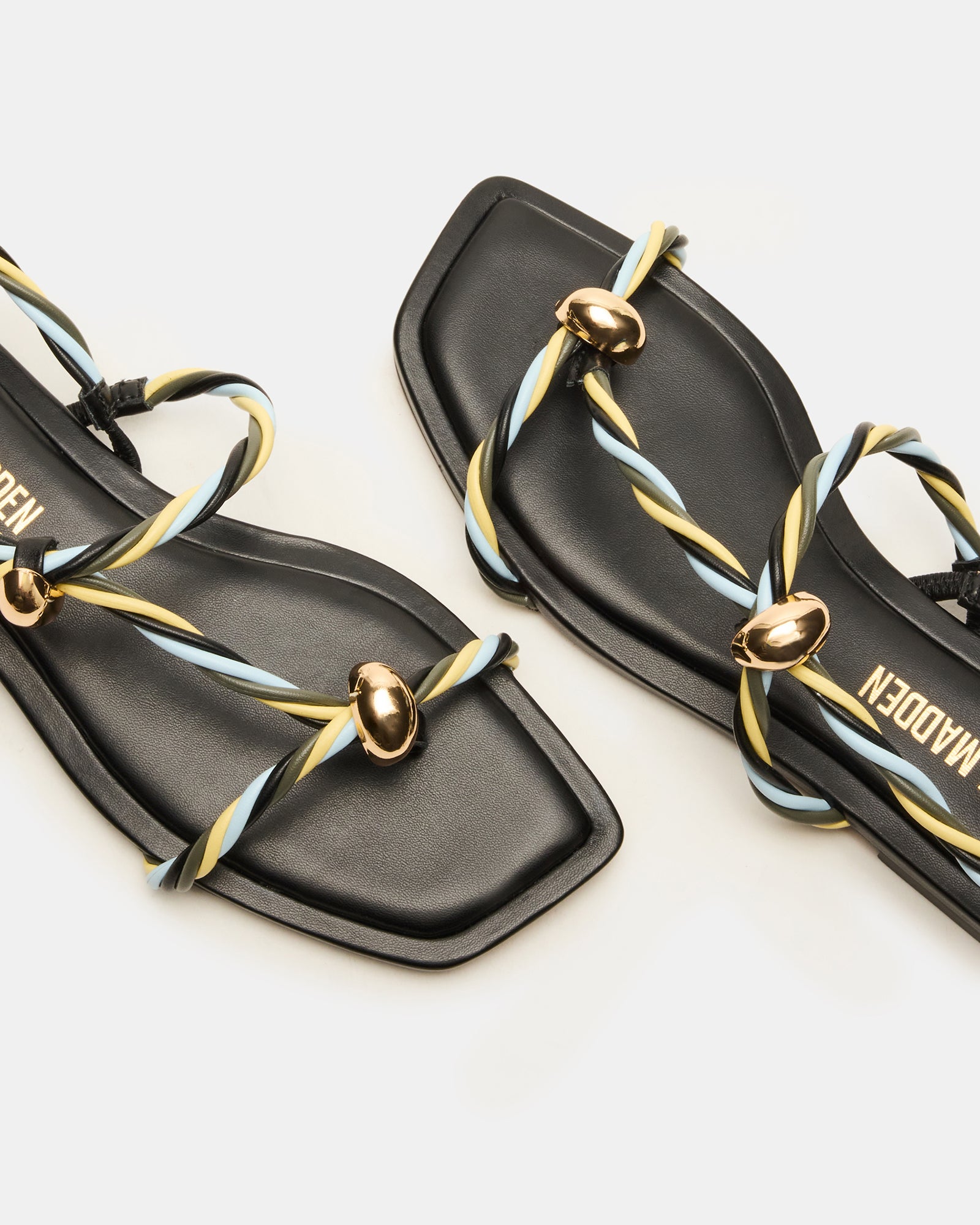 Black strappy sandals with a square toe on a models feet in a sunny park.