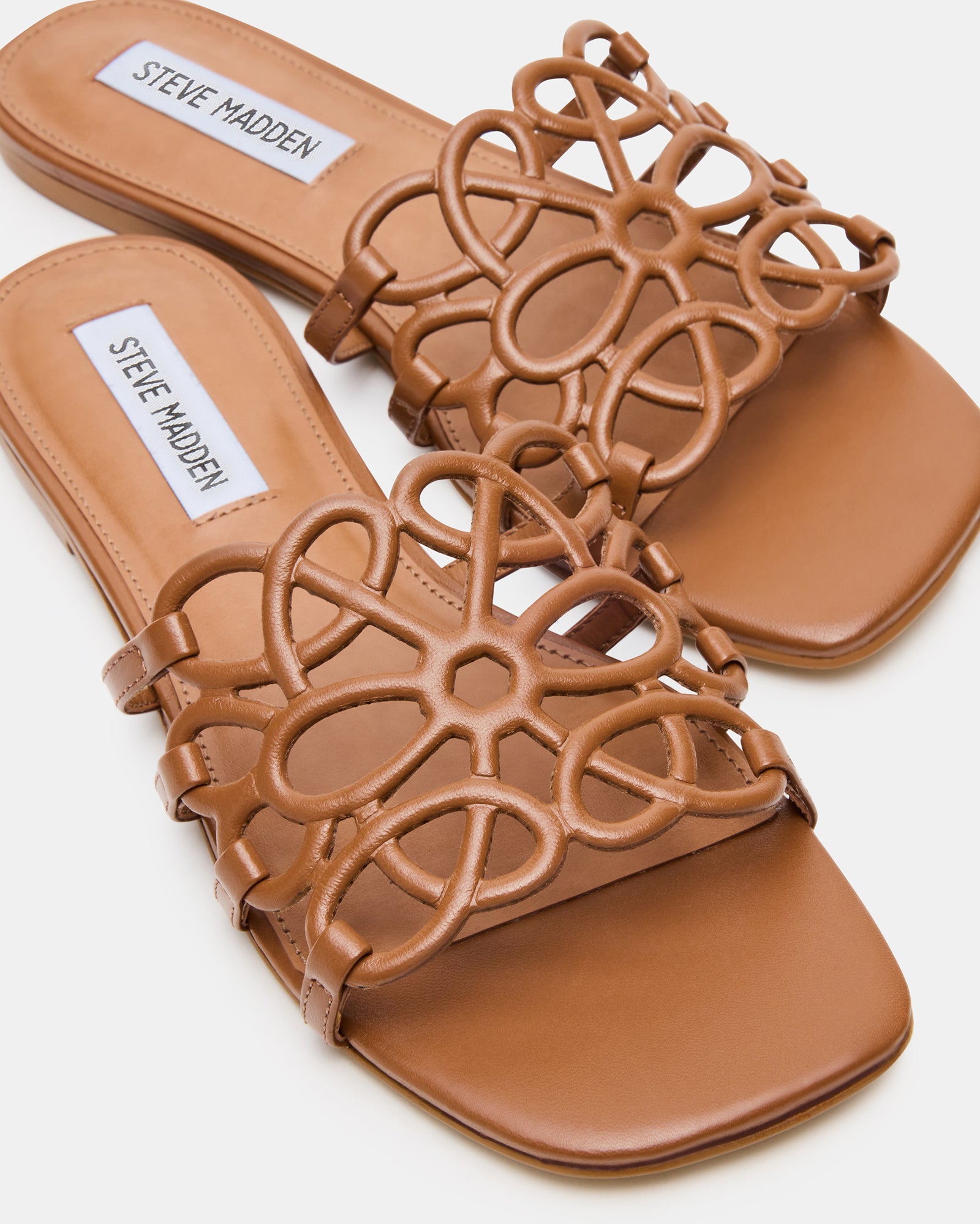 Side view of brown leather slide sandals highlighting the synthetic sole