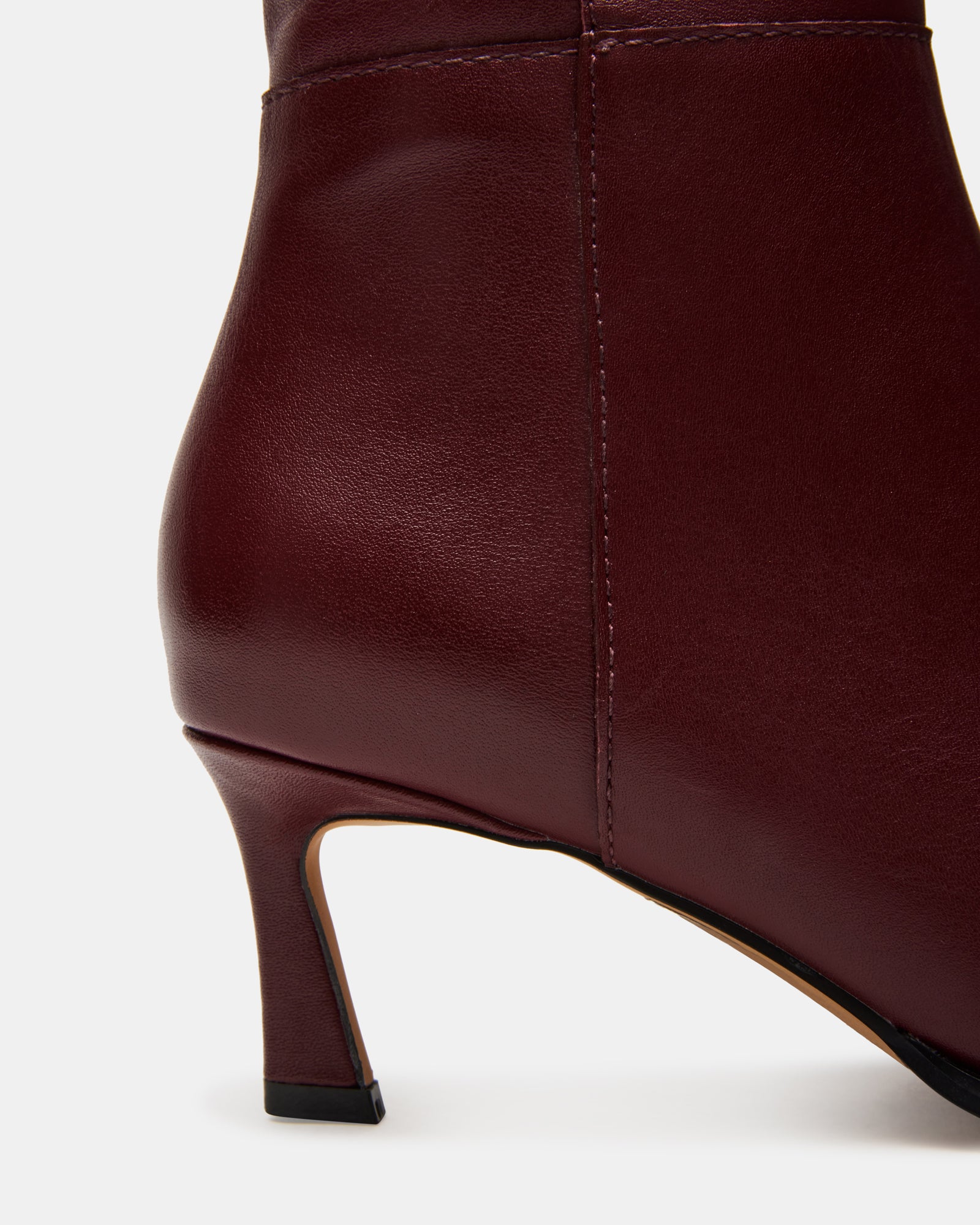 Close-up of burgundy knee-high boots with pointed toe and kitten heel
