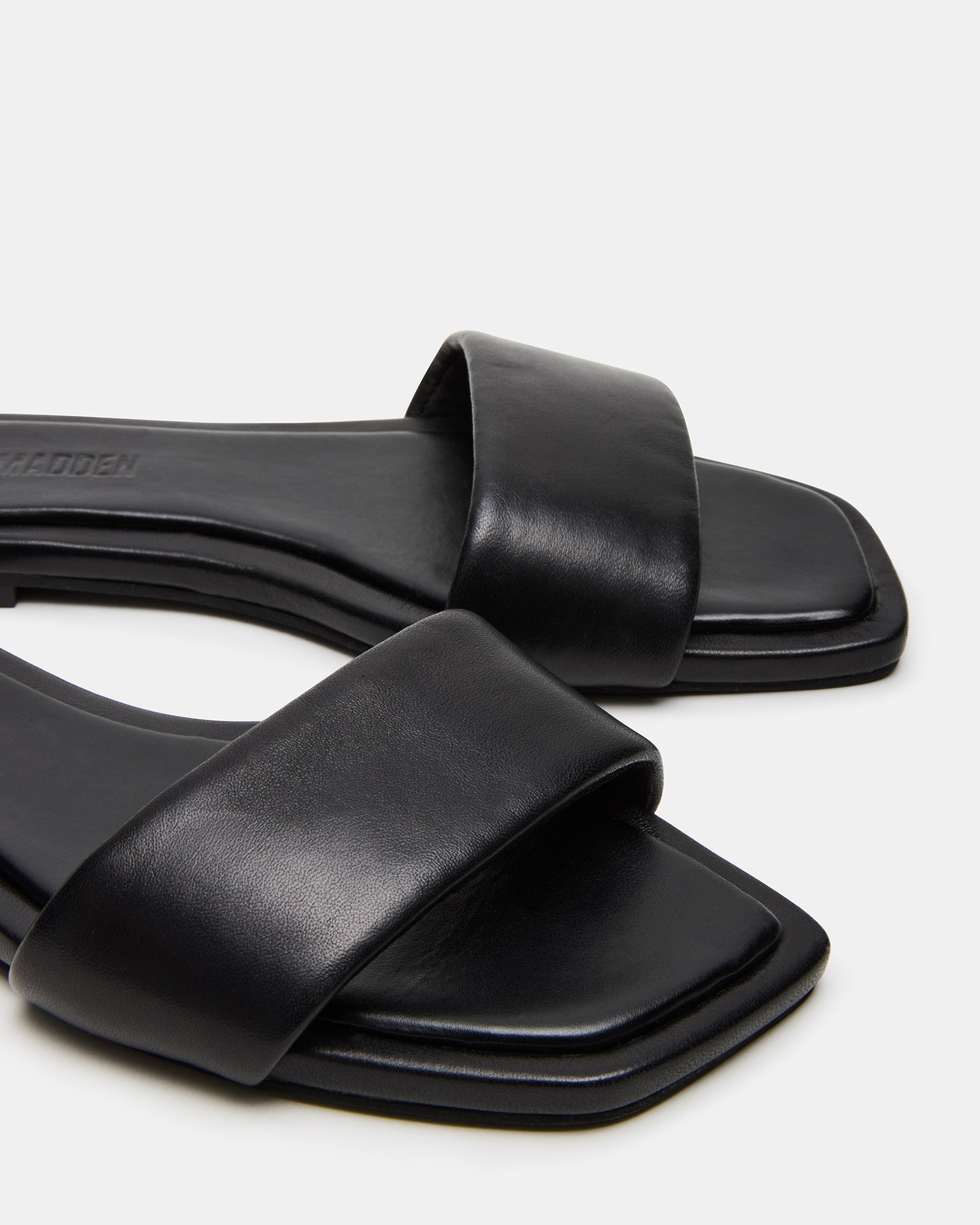 Side view of Lumina black leather sandals on a model’s foot, showcasing the minimalist design
