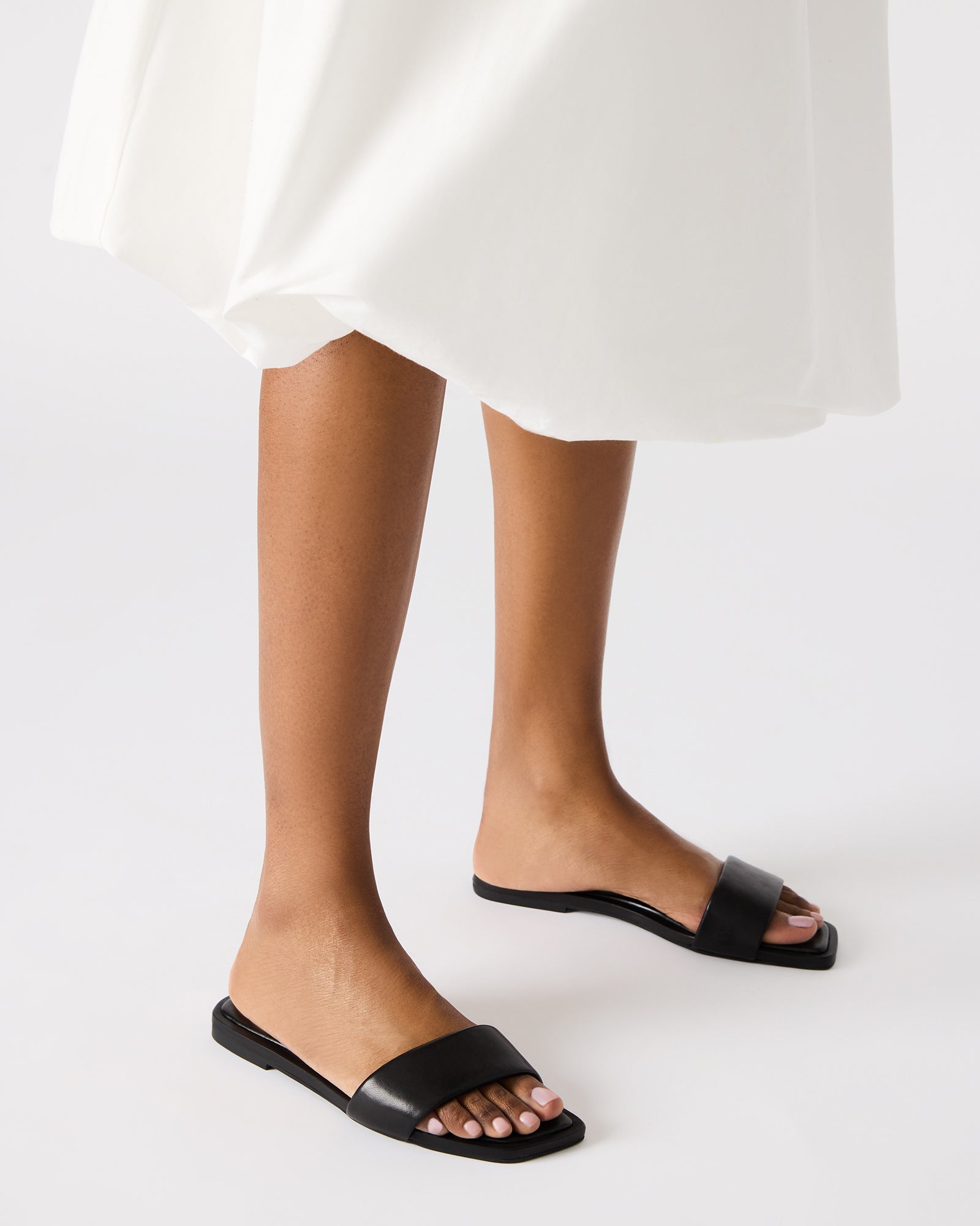 Woman wearing LUMINA rhinestone sandals, showcasing versatility.