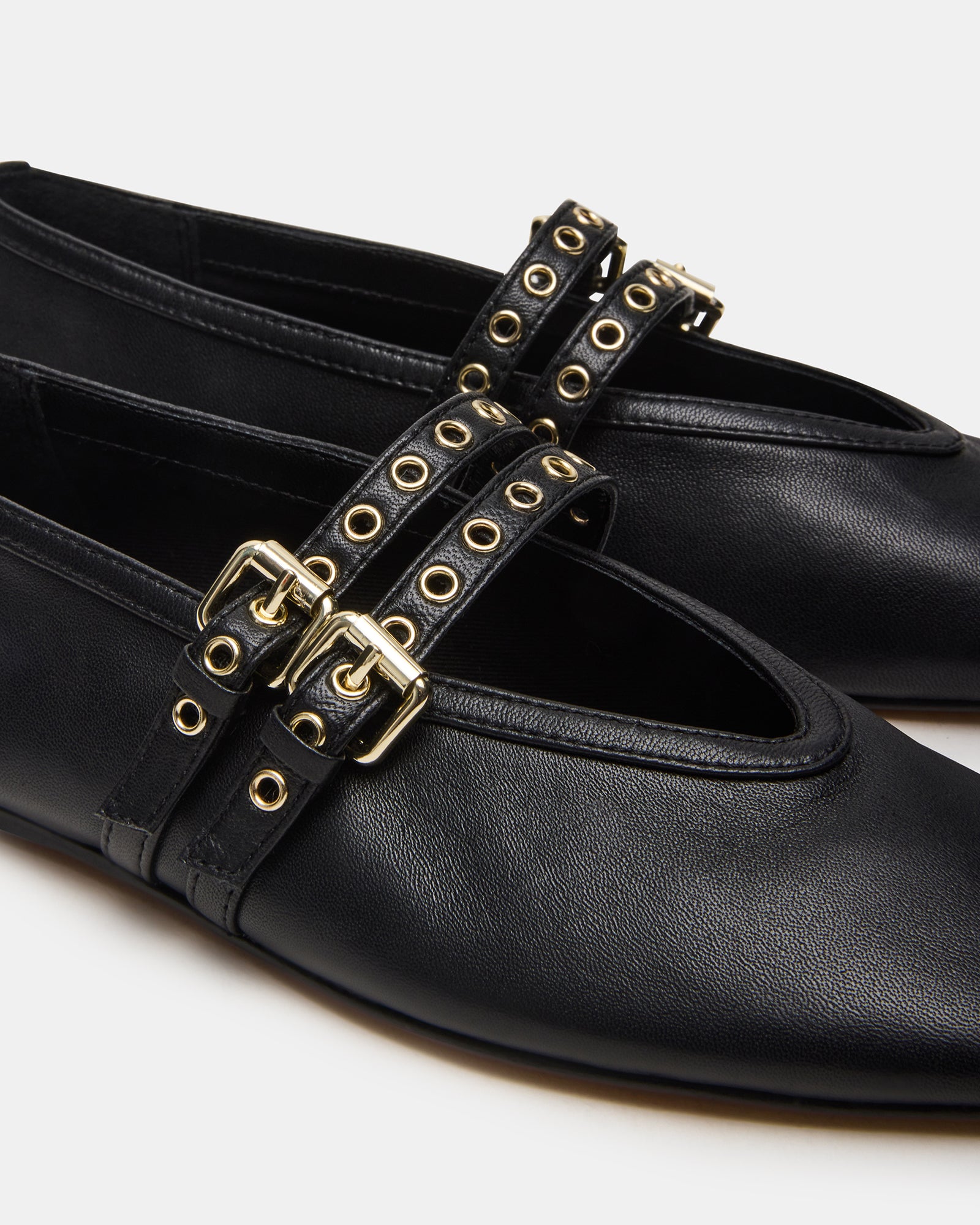 Lifestyle image of model wearing black ballet flats on a cafe sidewalk
