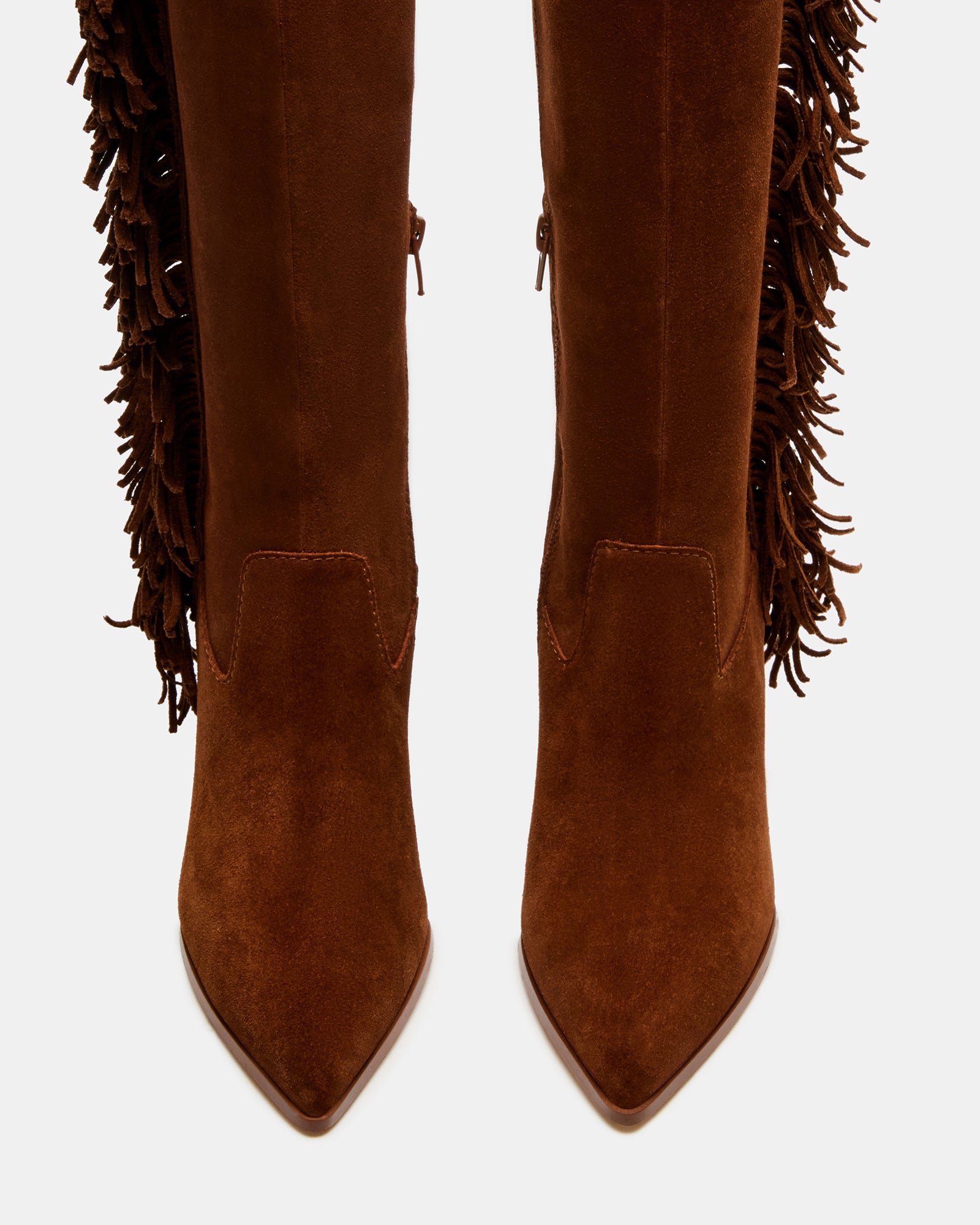 Side profile of fringe cowboy boots with angular heel against desert landscape