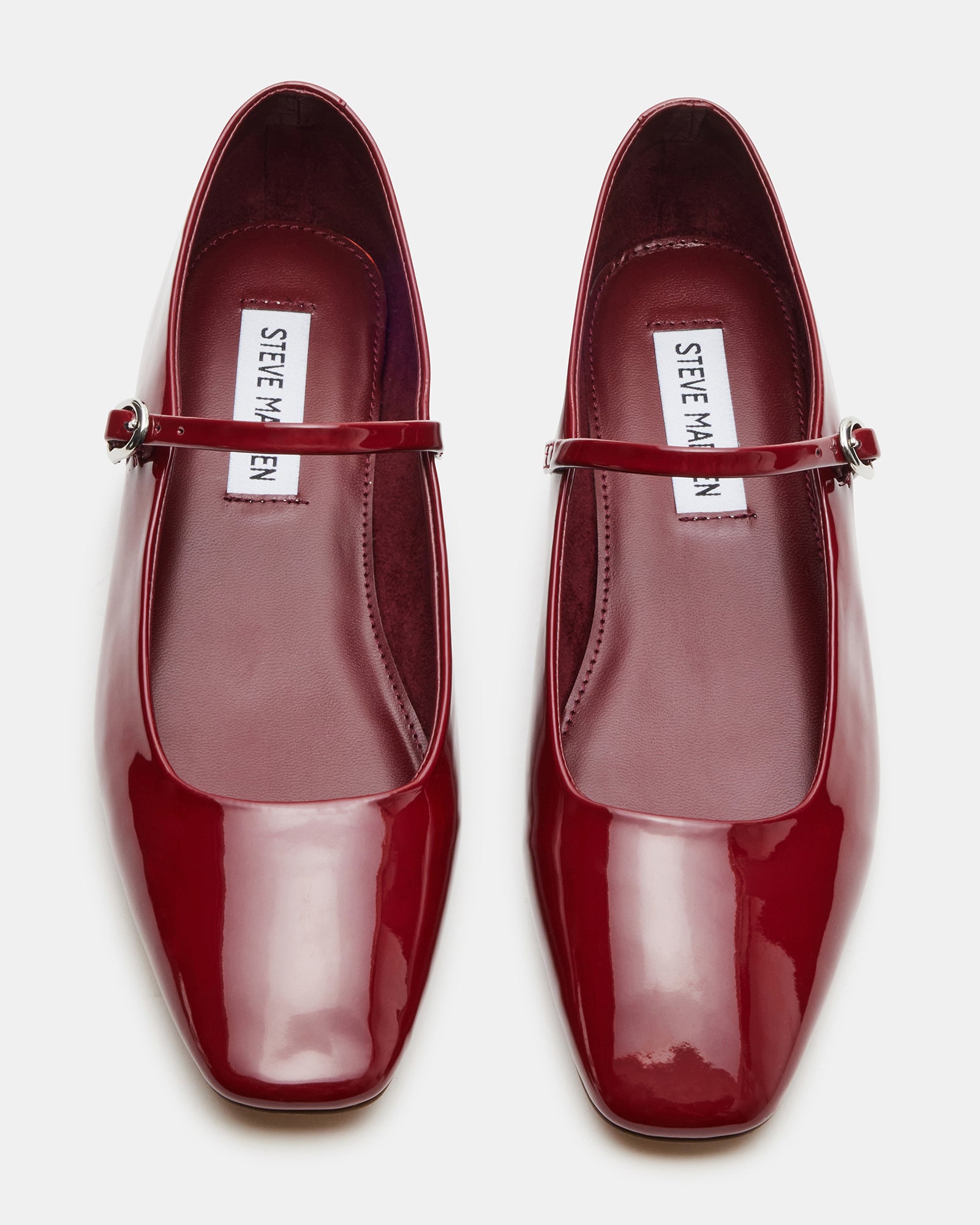 Model walking through city streets wearing Mary Jane shoes in red with cropped trousers