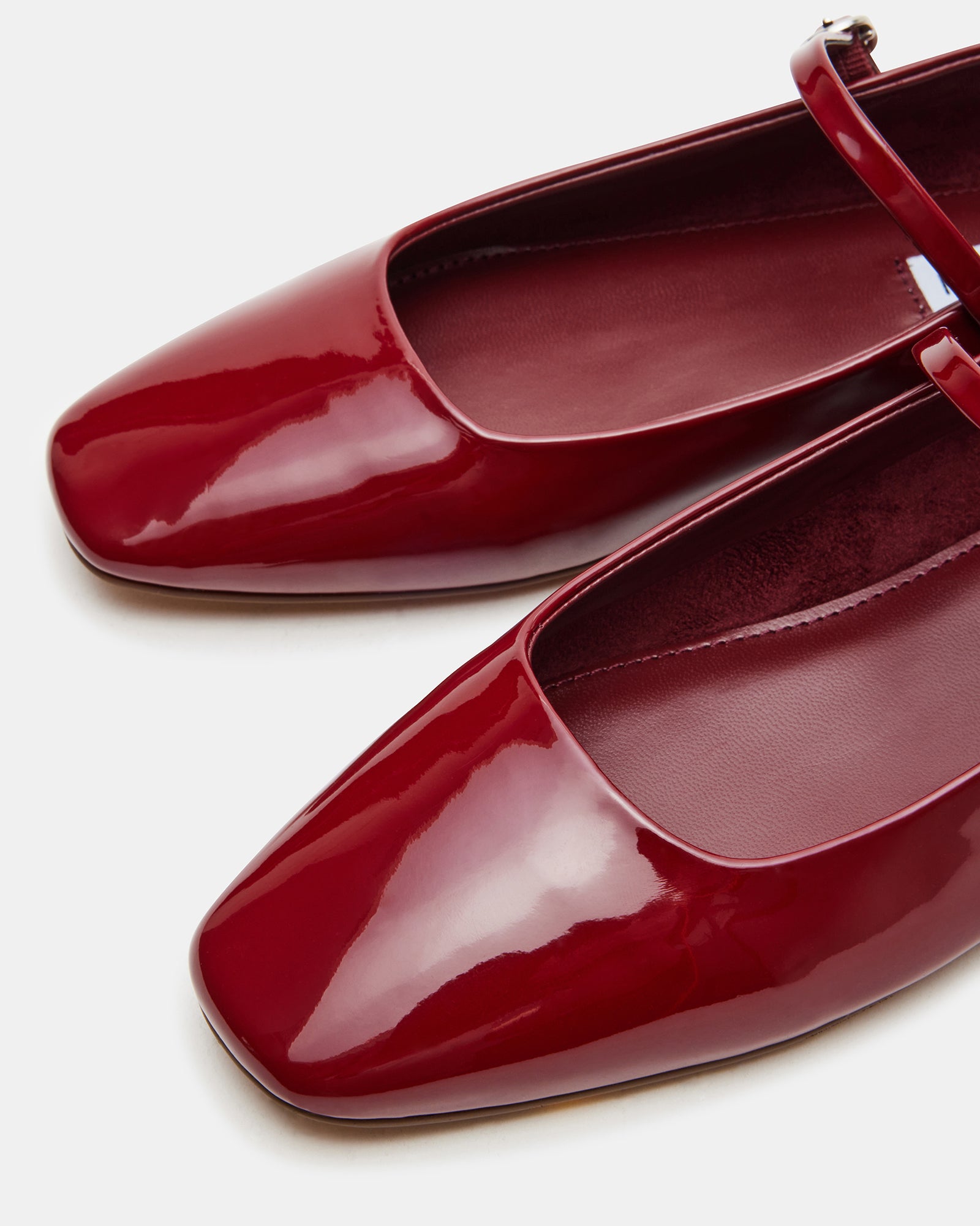 Close-up side view of red ballet flats showing square toe shape and glossy finish