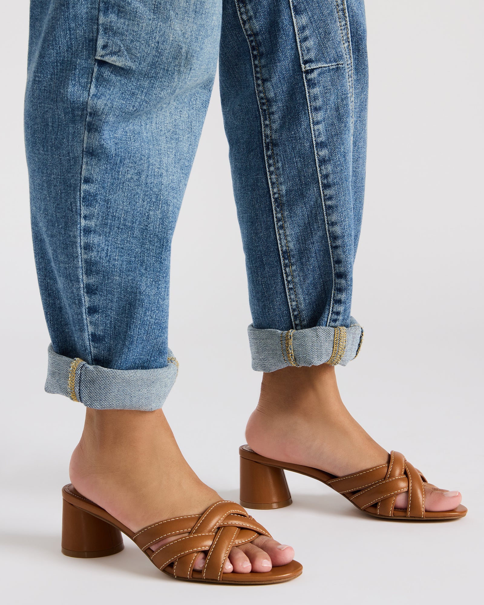 Side view of block heeled mules paired with cropped trousers