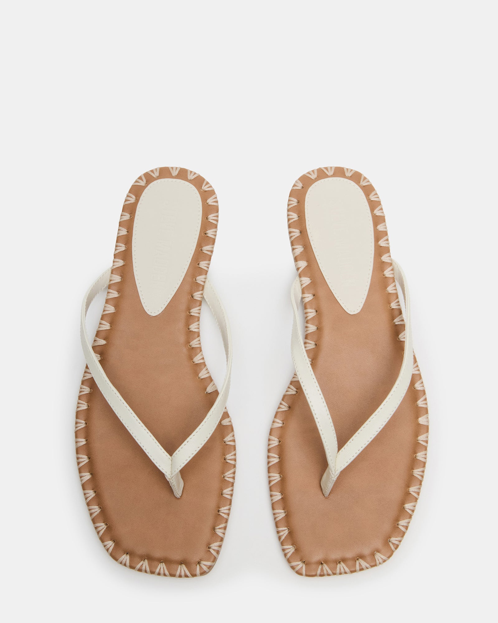 Top-down perspective of square toe thong sandals on wooden floor